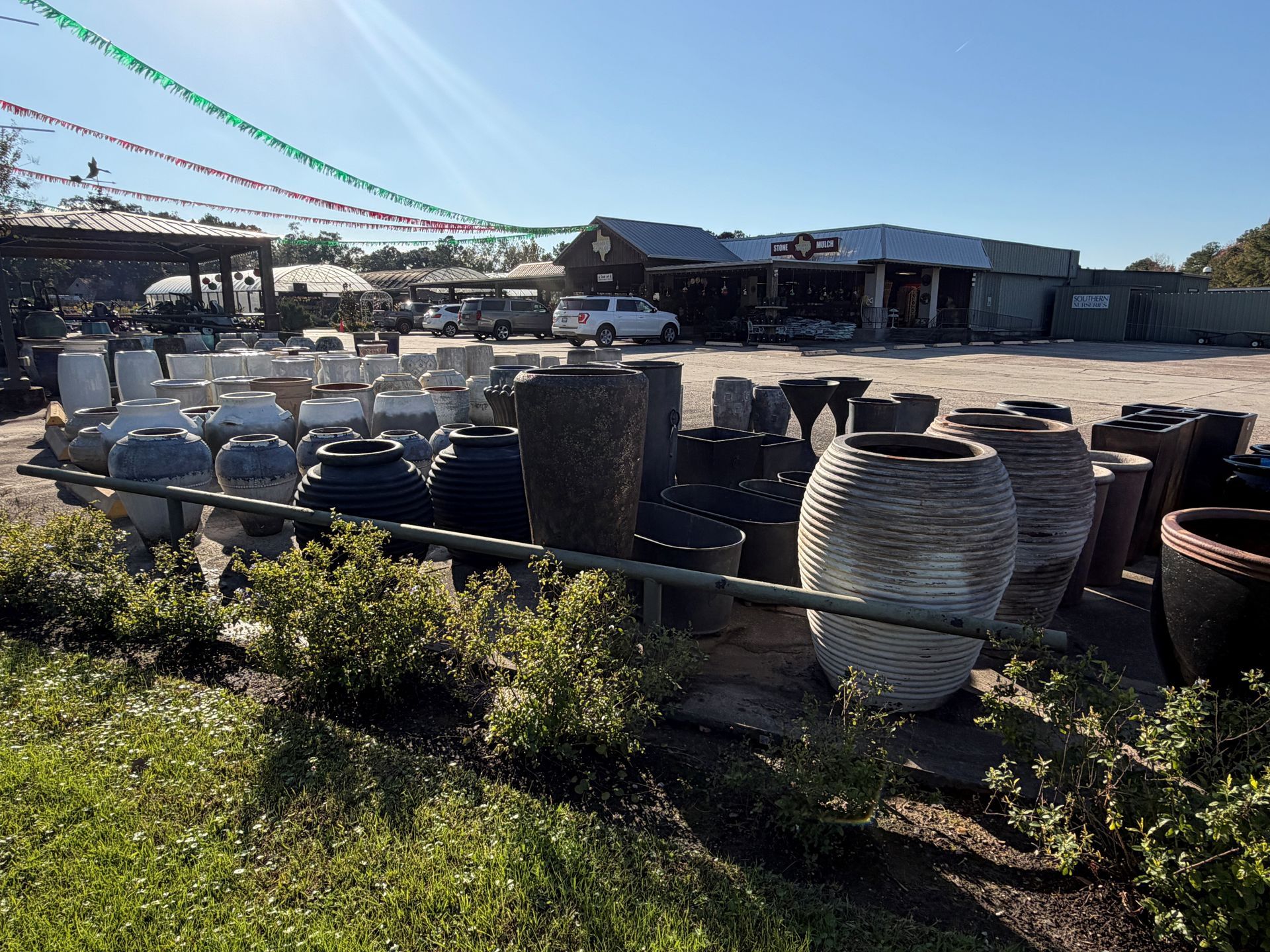 Assortment of ceramic pots of various sizes and textures in an outdoor garden center setting.