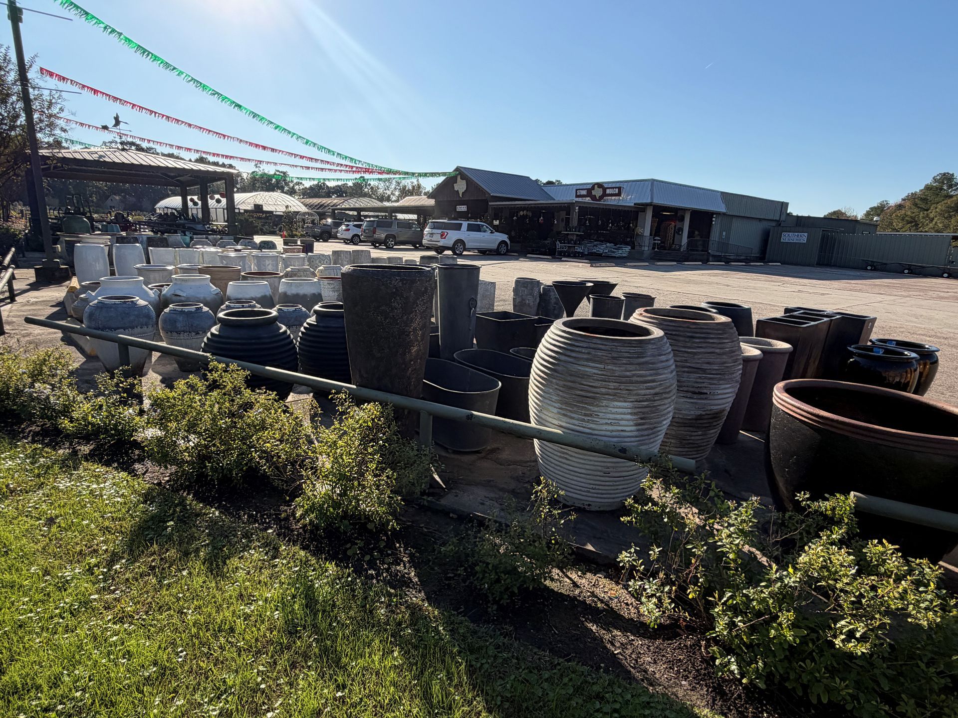 Pots and planters displayed outside a garden center on a sunny day.