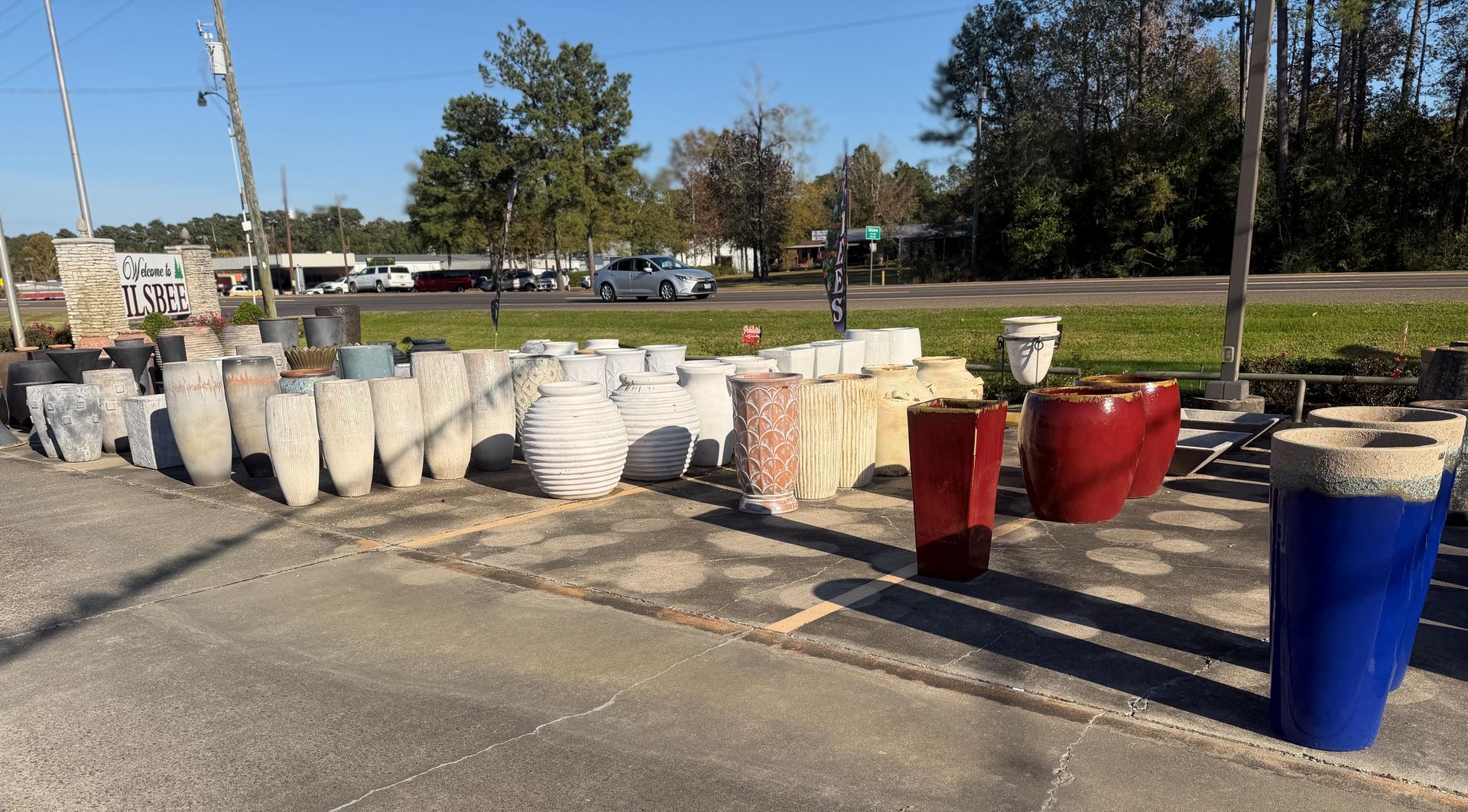 A display of various concrete and glazed planters in a roadside shop.