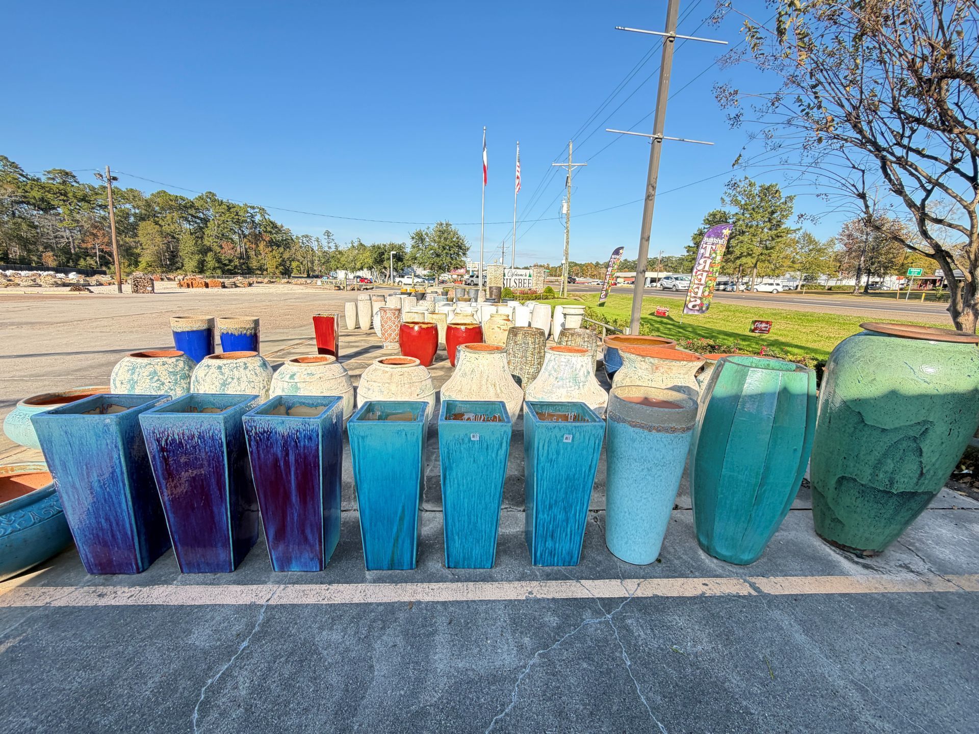 Rows of various colored ceramic planters outdoors in a sunny setting.