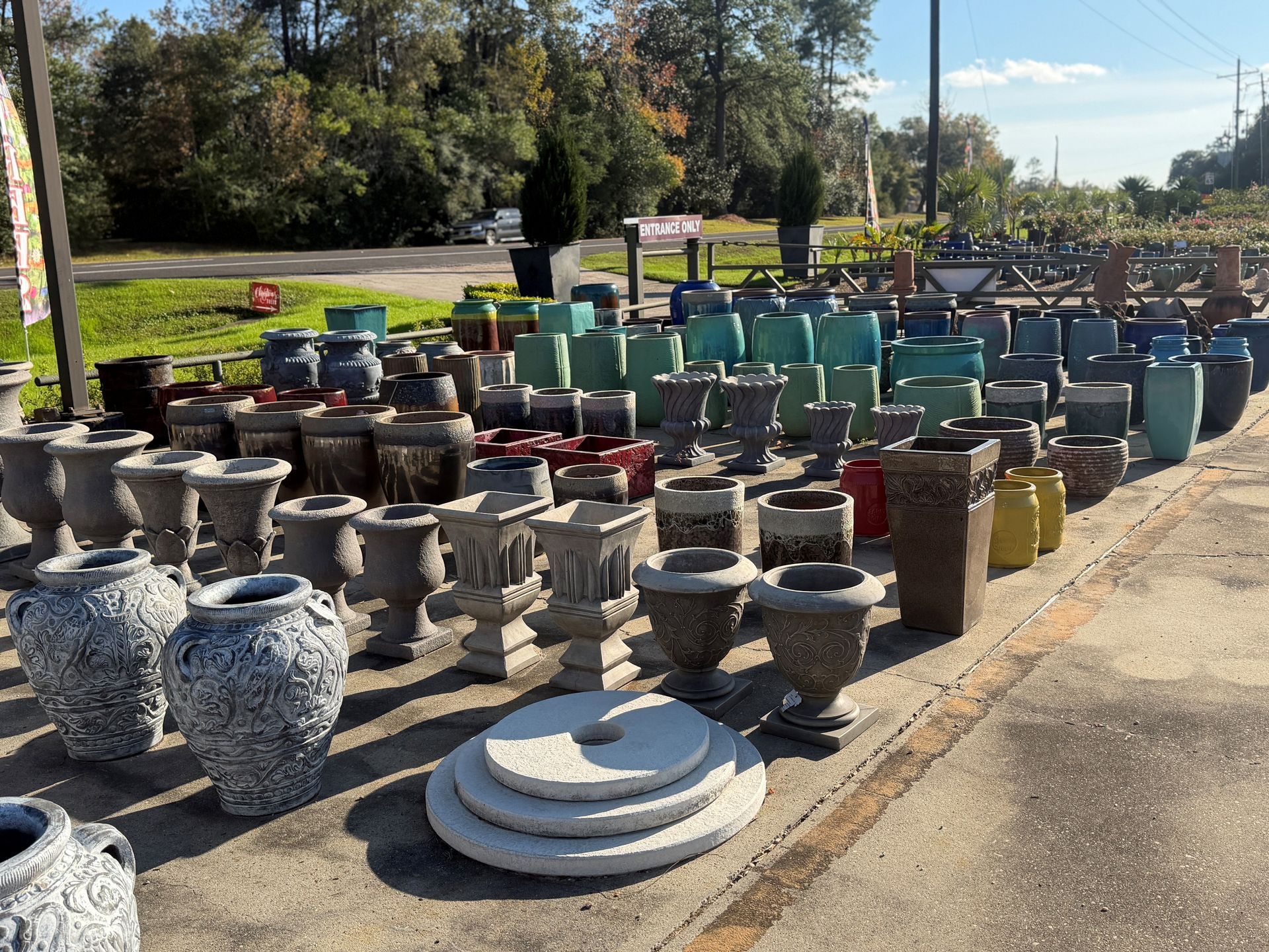 Rows of various ceramic pots in assorted colors and styles displayed outdoors.