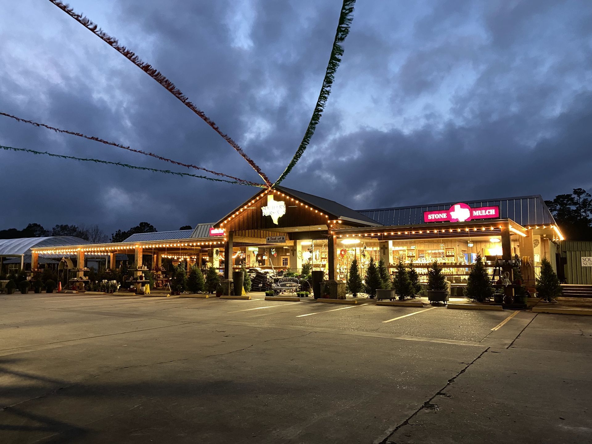 Storefront at dusk, Texas flag emblem, strings of lights, cloudy sky.