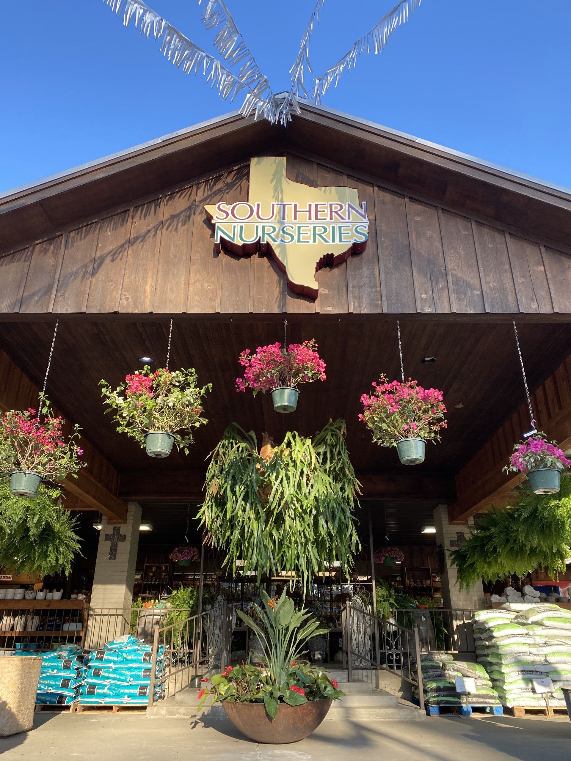 Entrance to Southern Nurseries with hanging flower baskets and Texas-shaped logo.