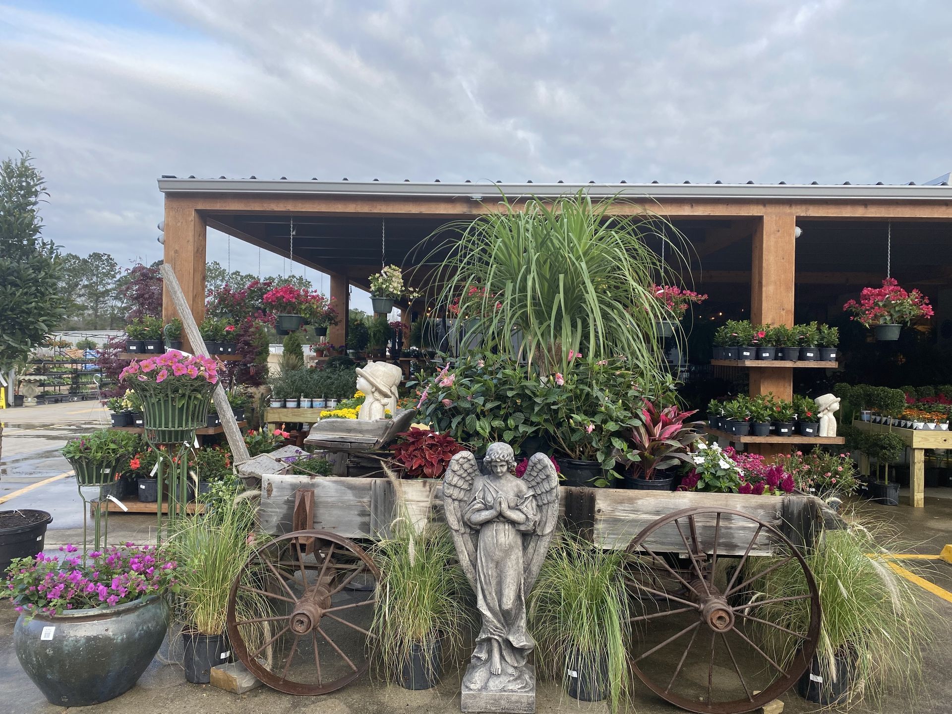 Garden center display with potted plants, angel statue, and decorative wagon.