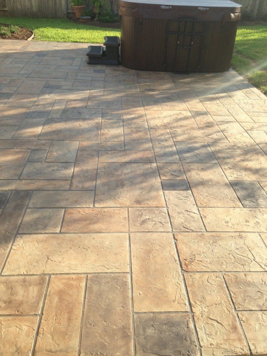 A hot tub is sitting on a patio next to a brick walkway.
