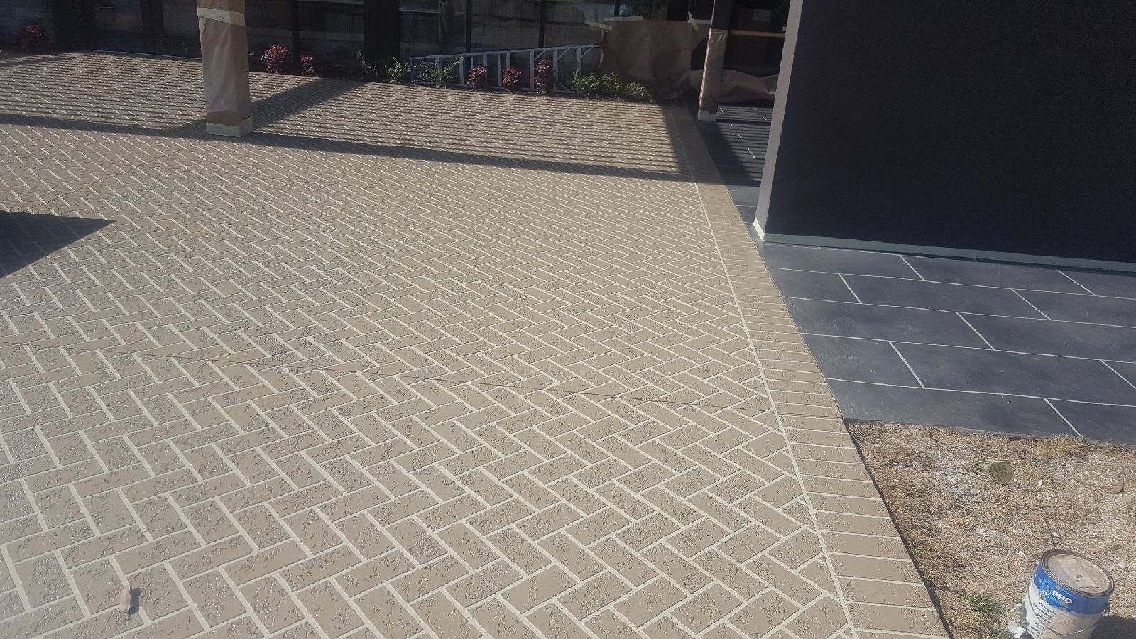 A brick driveway with a herringbone pattern in front of a building.