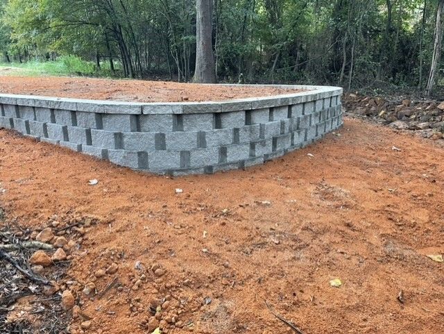 A brick wall is sitting in the middle of a dirt field.