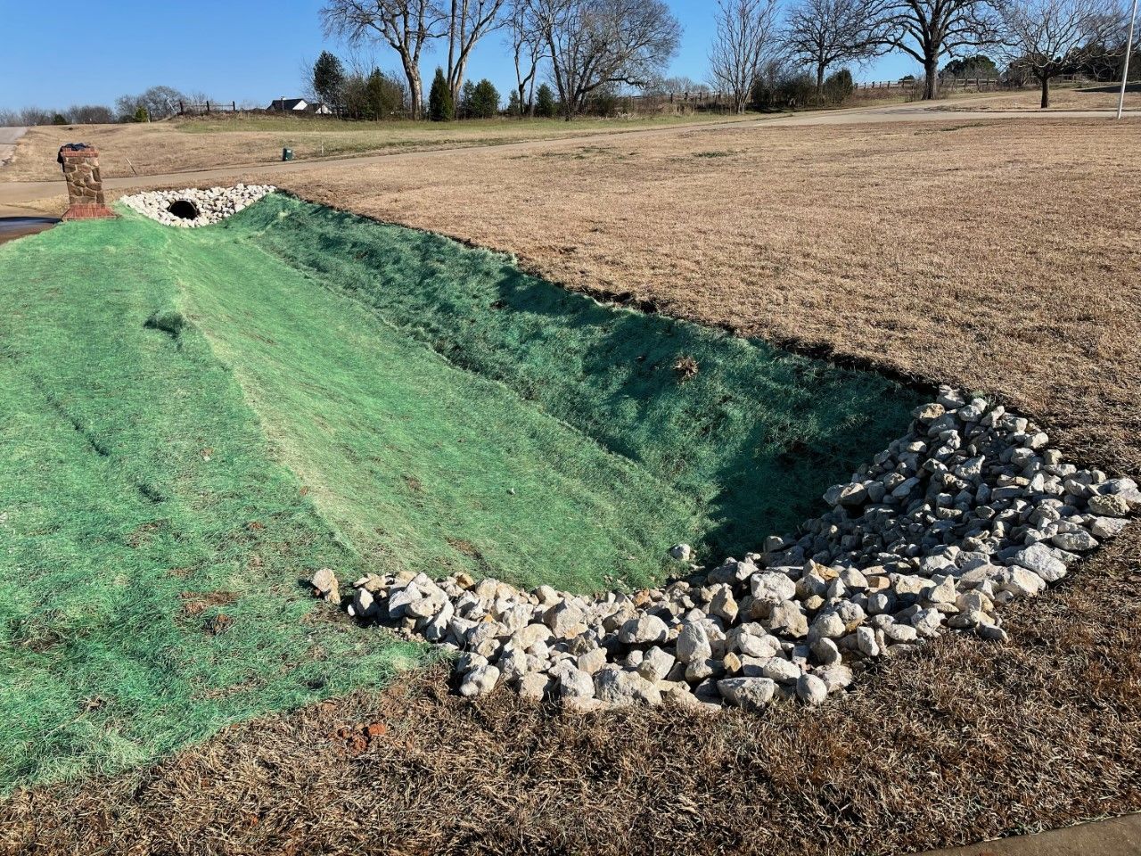 A large pile of grass and rocks is sitting in the middle of a field.