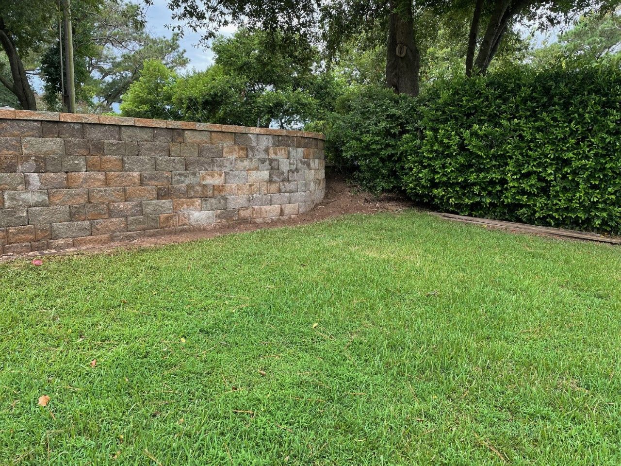 A brick wall surrounds a lush green lawn.