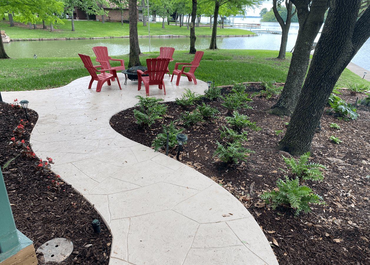 A patio with red chairs and a table with a lake in the background
