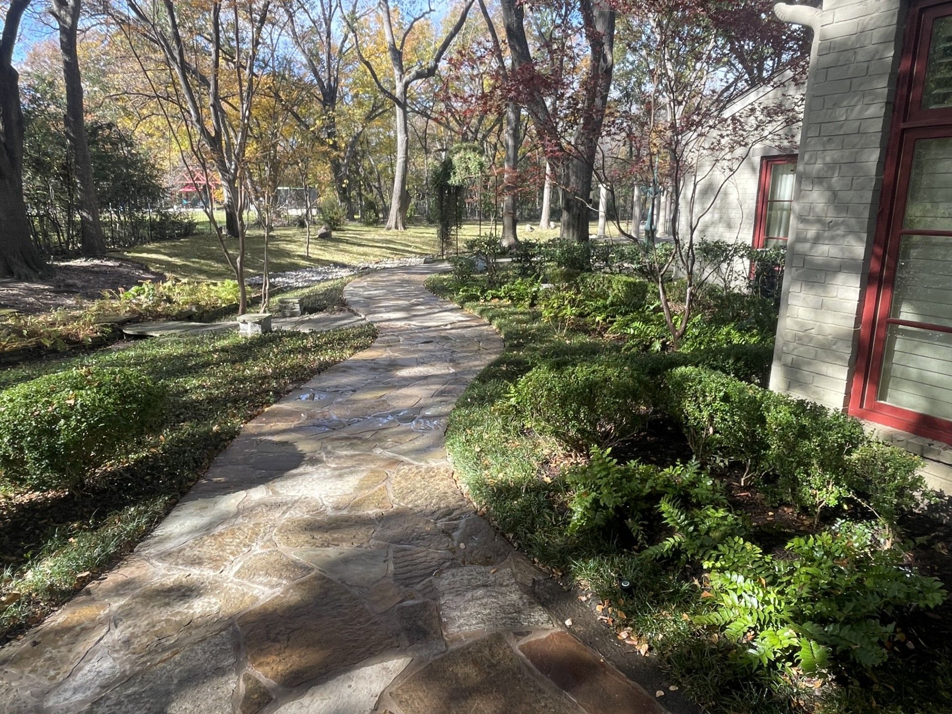 a stone walkway leading to a house surrounded by trees and bushes .