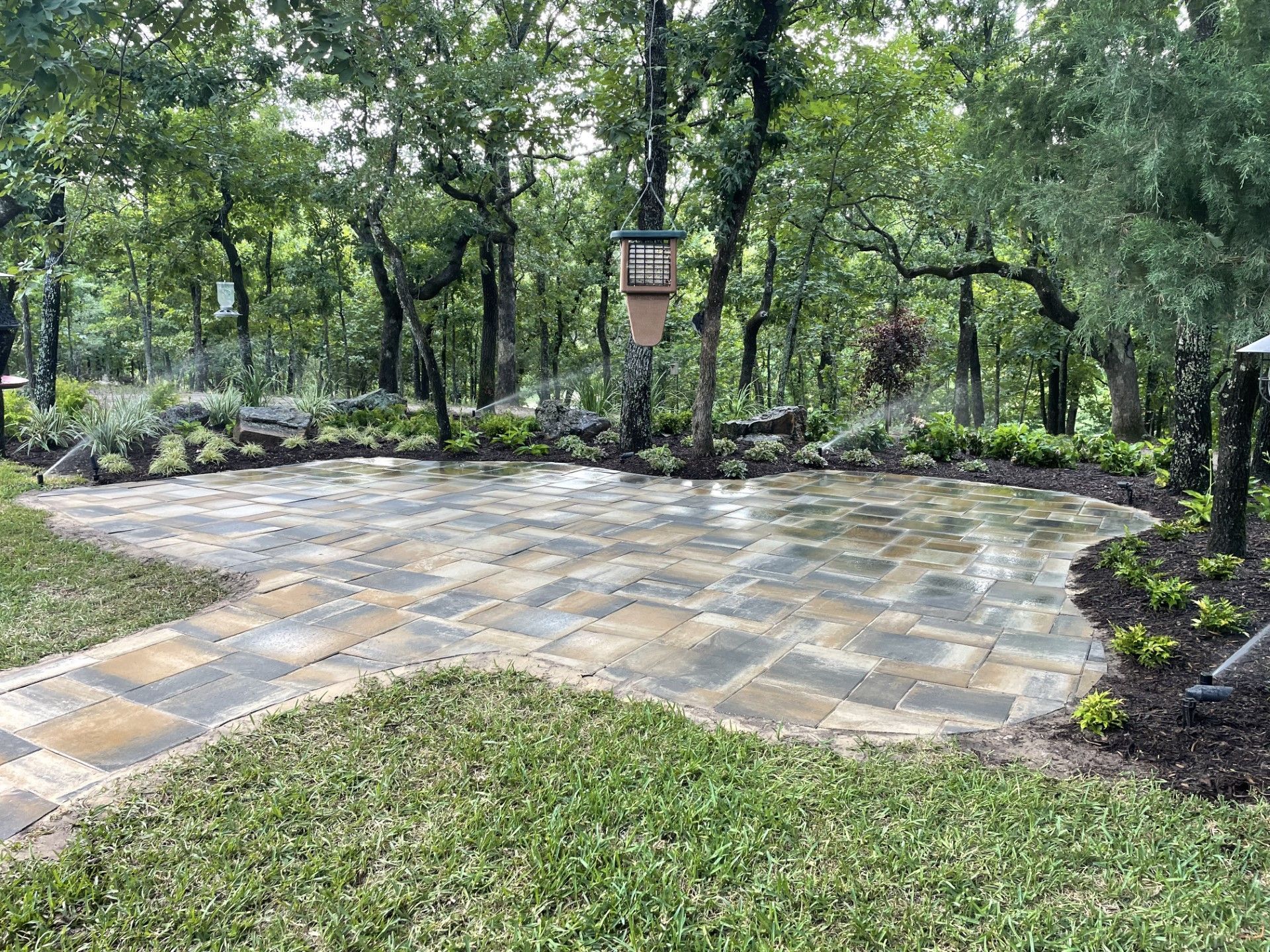 a patio in the middle of a lush green field with trees in the background .
