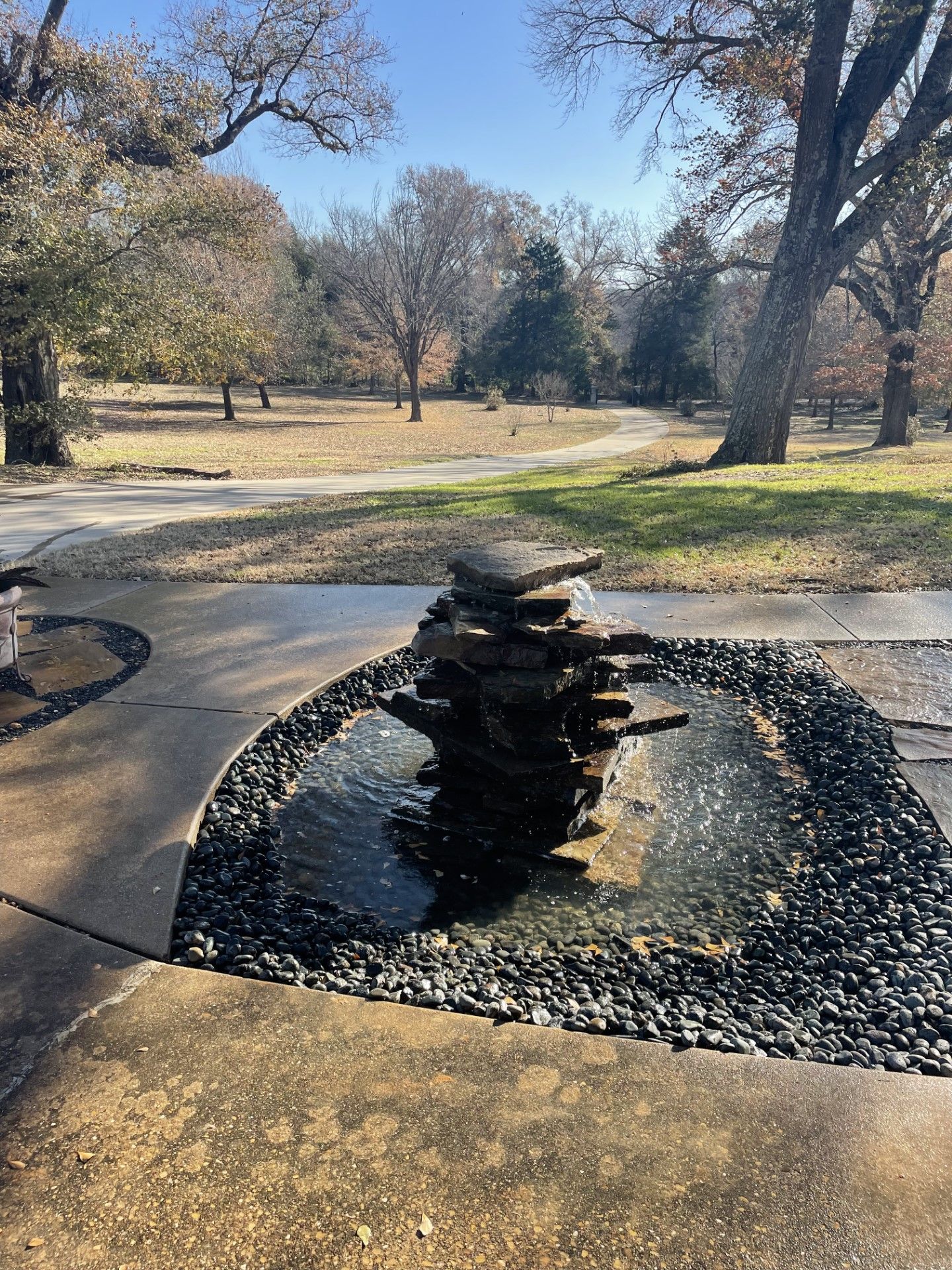 A fountain in the middle of a park with trees in the background.