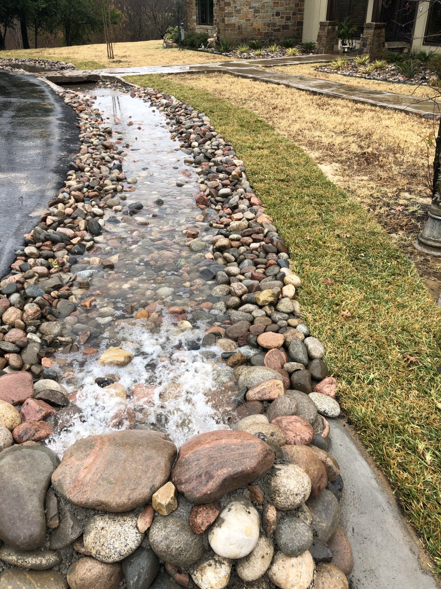 A stream of water is surrounded by rocks in a yard.