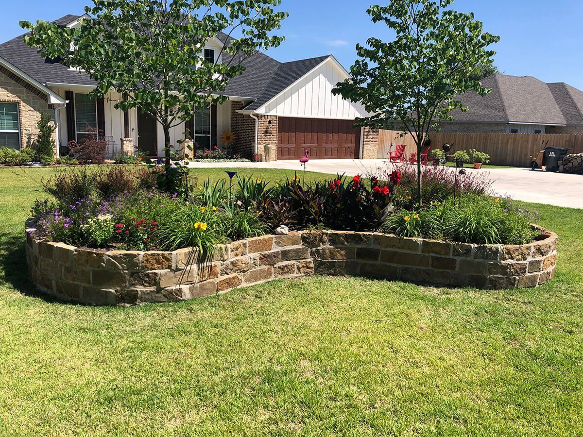 A house with a lush green lawn and a brick garden in front of it.