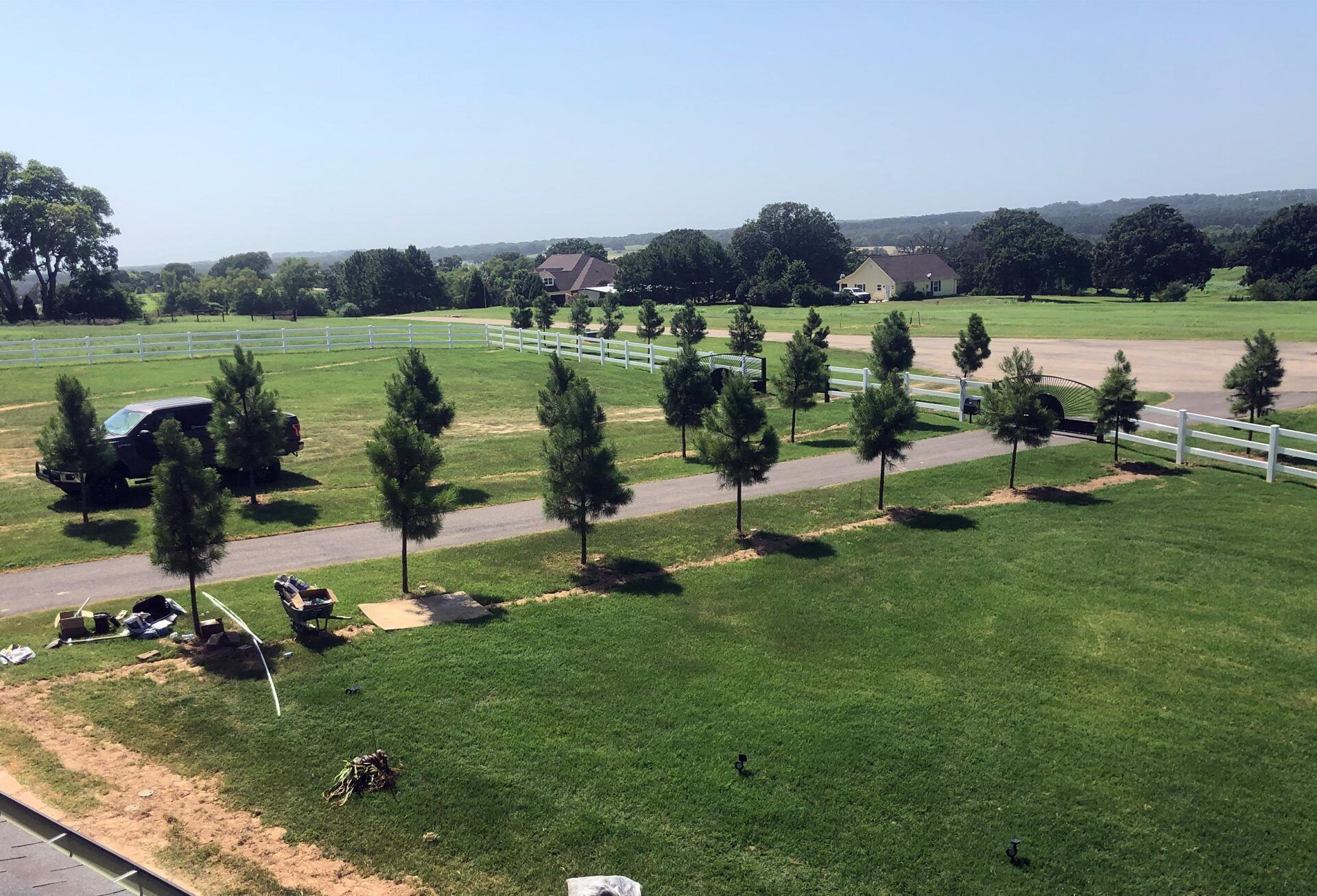 An aerial view of a large grassy field with trees and a road.