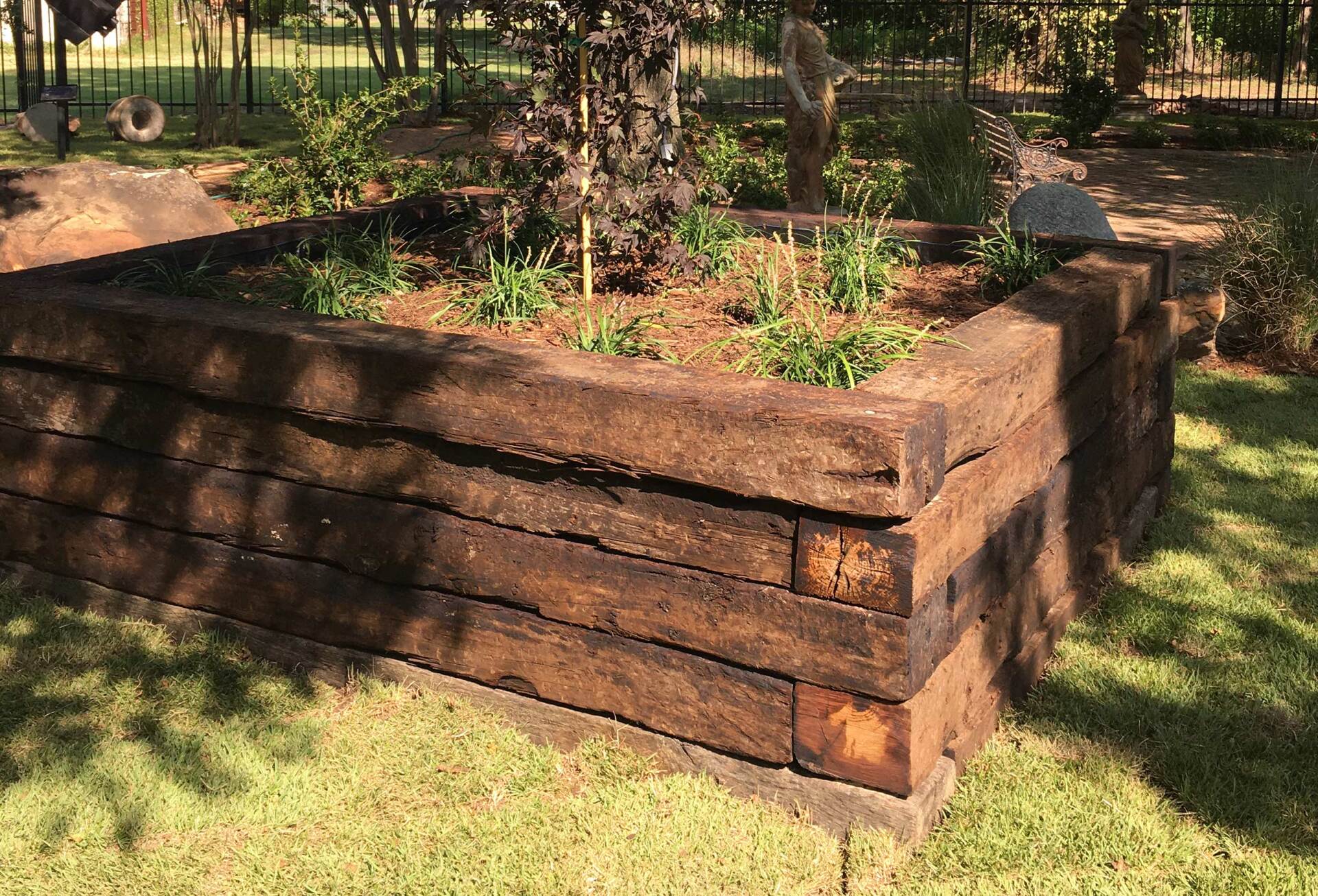 A wooden planter filled with plants is sitting on top of a lush green lawn.