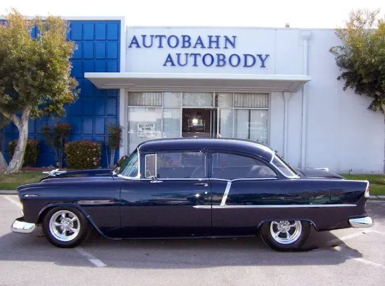Classic blue car parked in front of Autobahn Autobody shop.