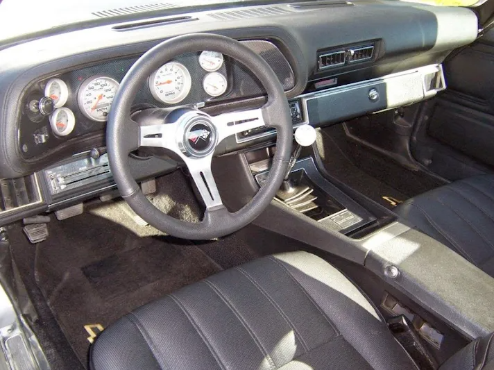 Black car interior: steering wheel, gauges, console, black seats.