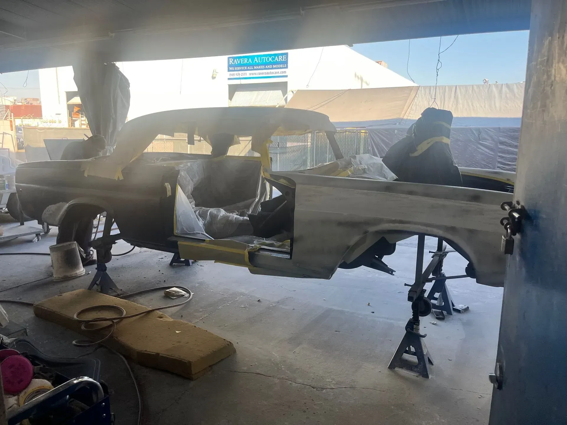Partially disassembled classic car on jack stands inside a garage.