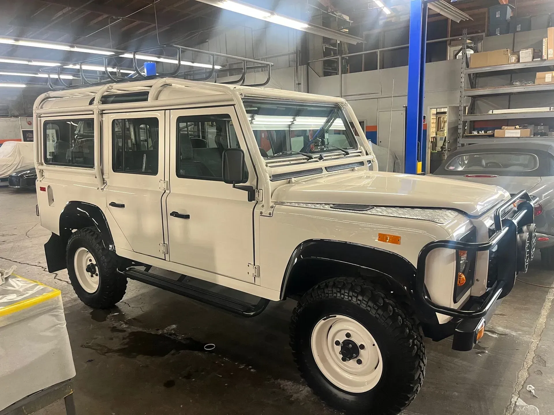 White Land Rover Defender with black accents parked inside a garage.
