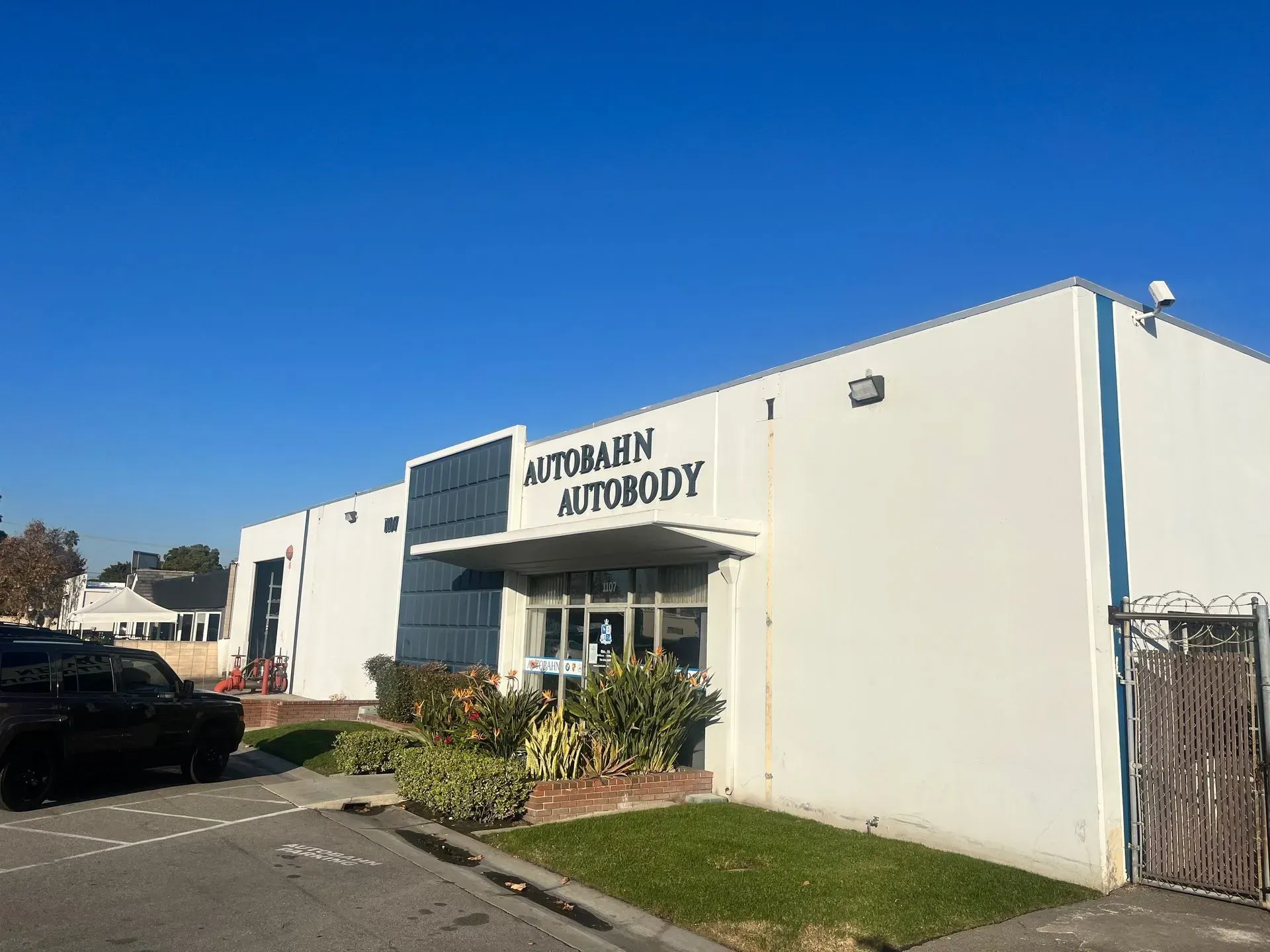 Autobahn Autobody building with a white exterior and a blue sky backdrop.