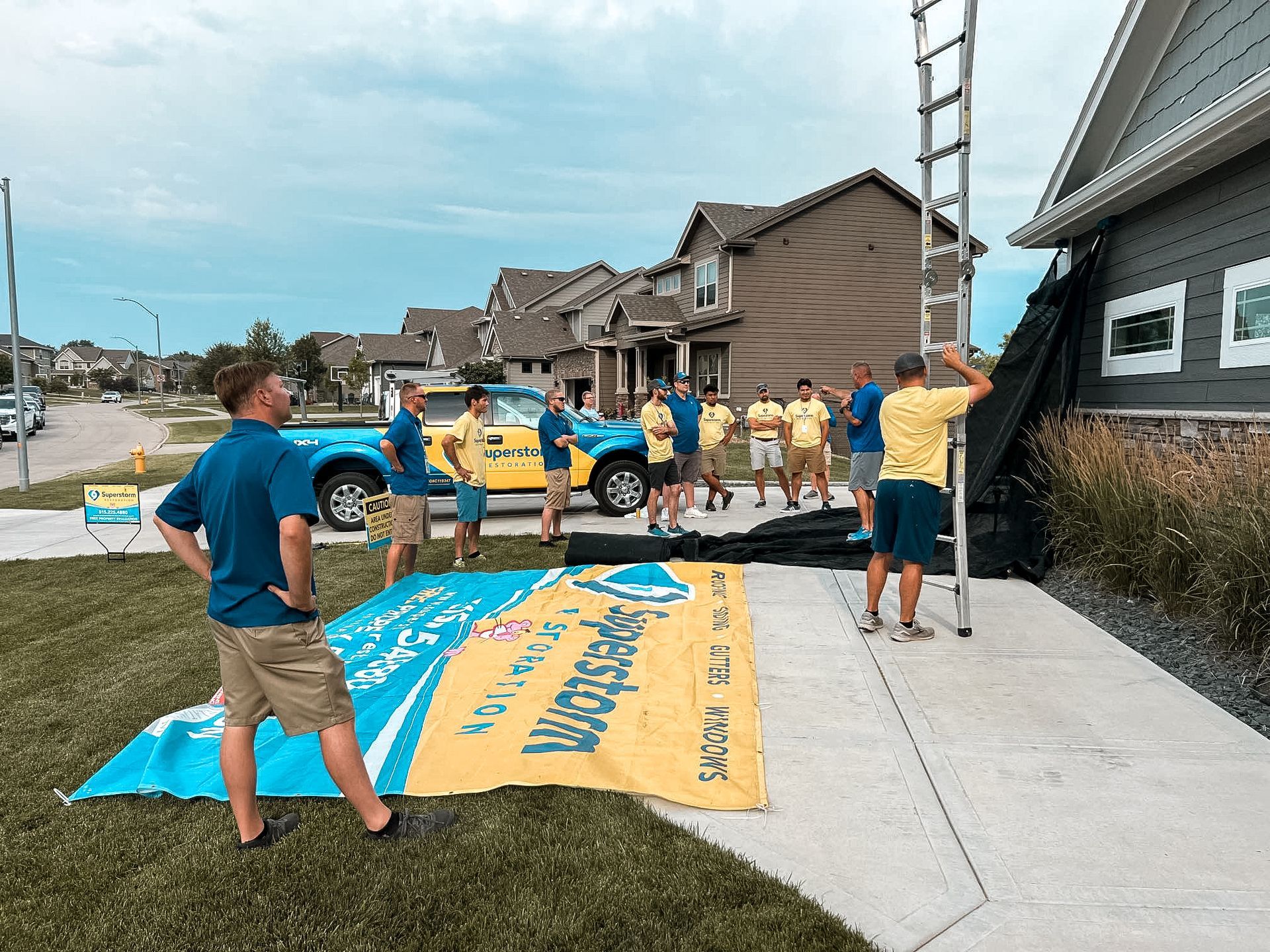 Group of roofers by a house, preparing to work. A ladder leans against the roof. Blue sky.