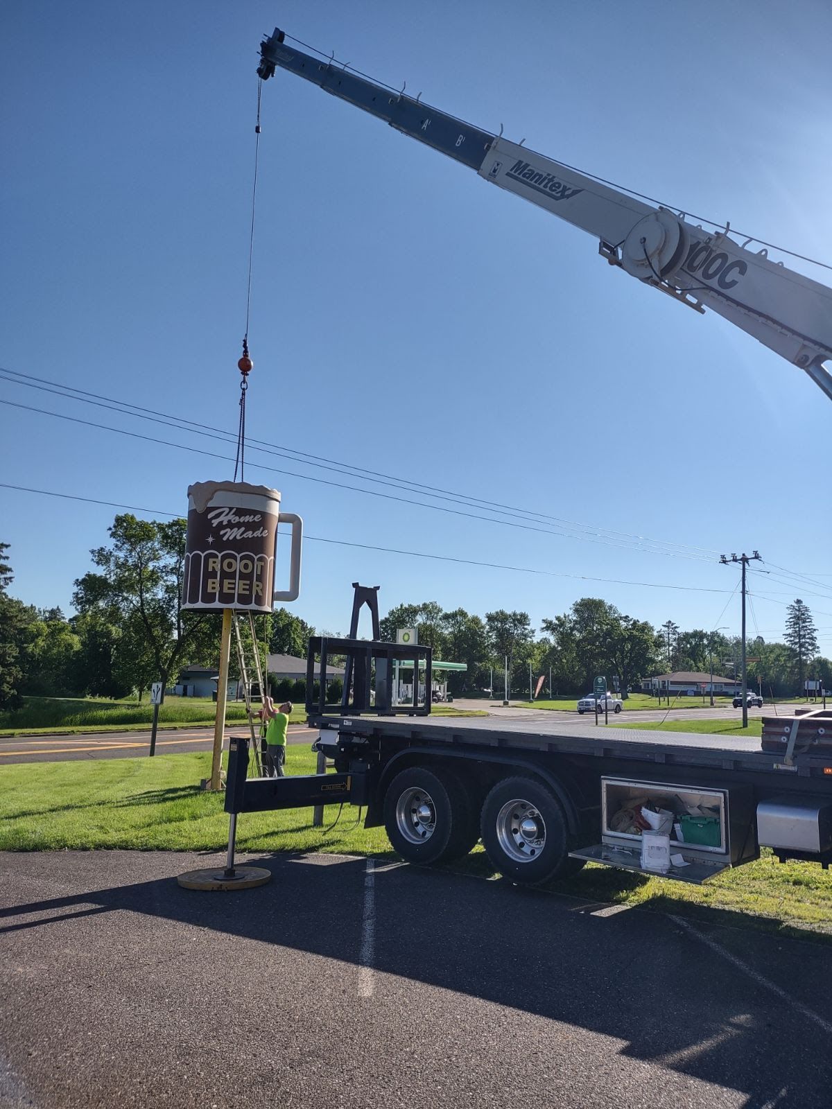 A truck with a crane attached to it is lifting a sign