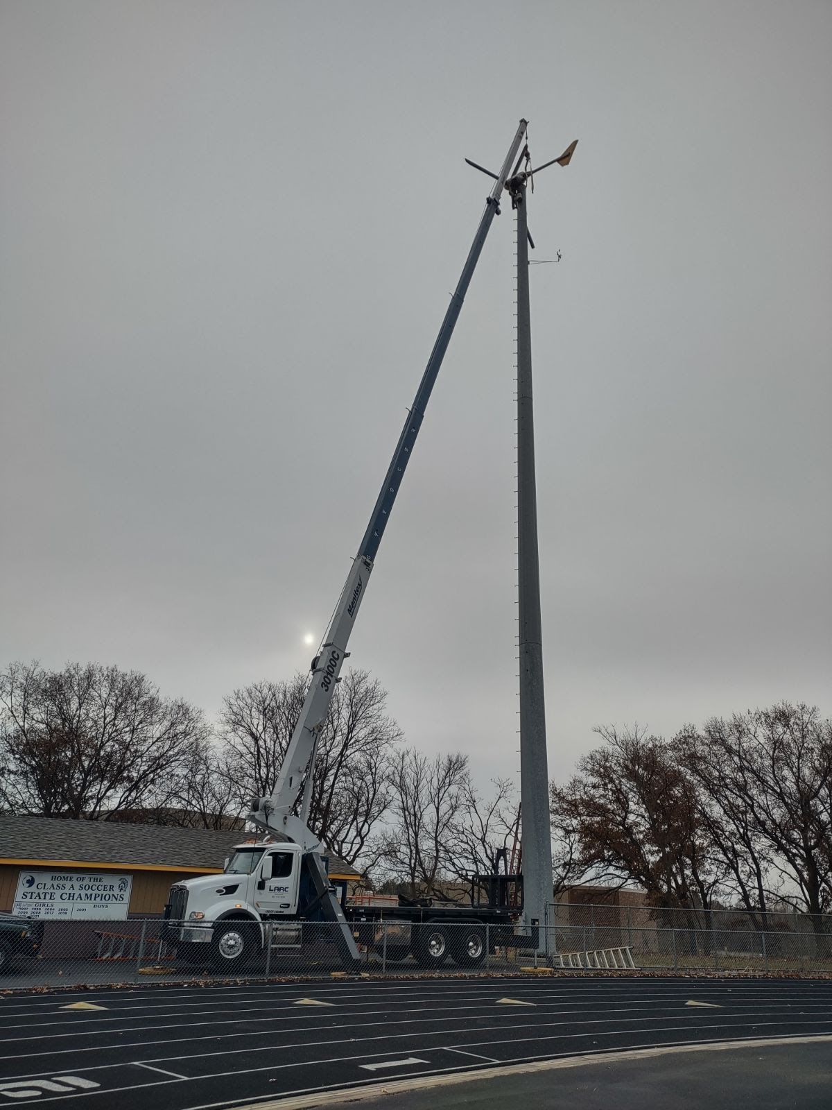 A truck with a crane attached to it is working on a pole