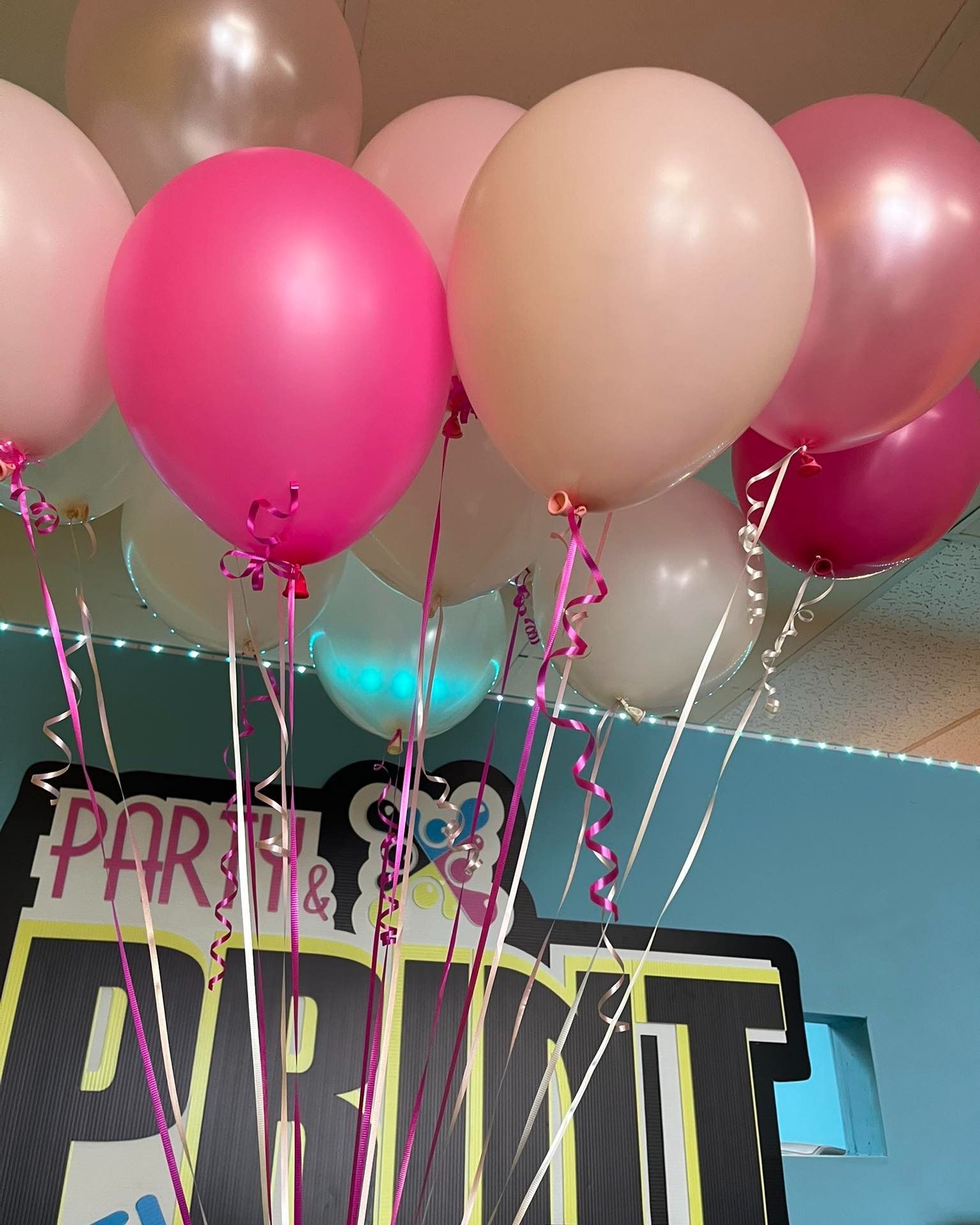 Pink and white balloons with ribbons near a 