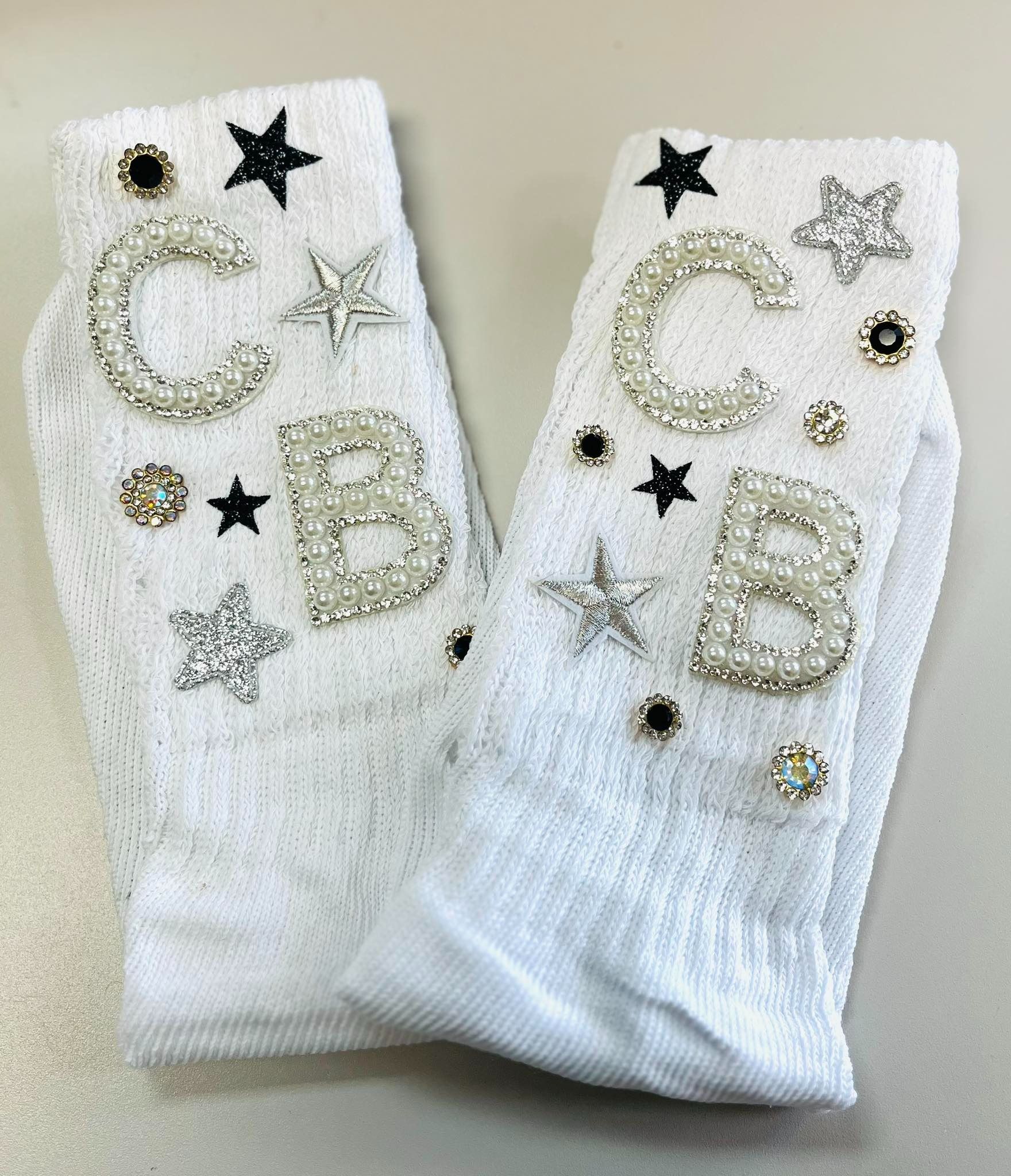 Pair of white socks decorated with rhinestone letters 