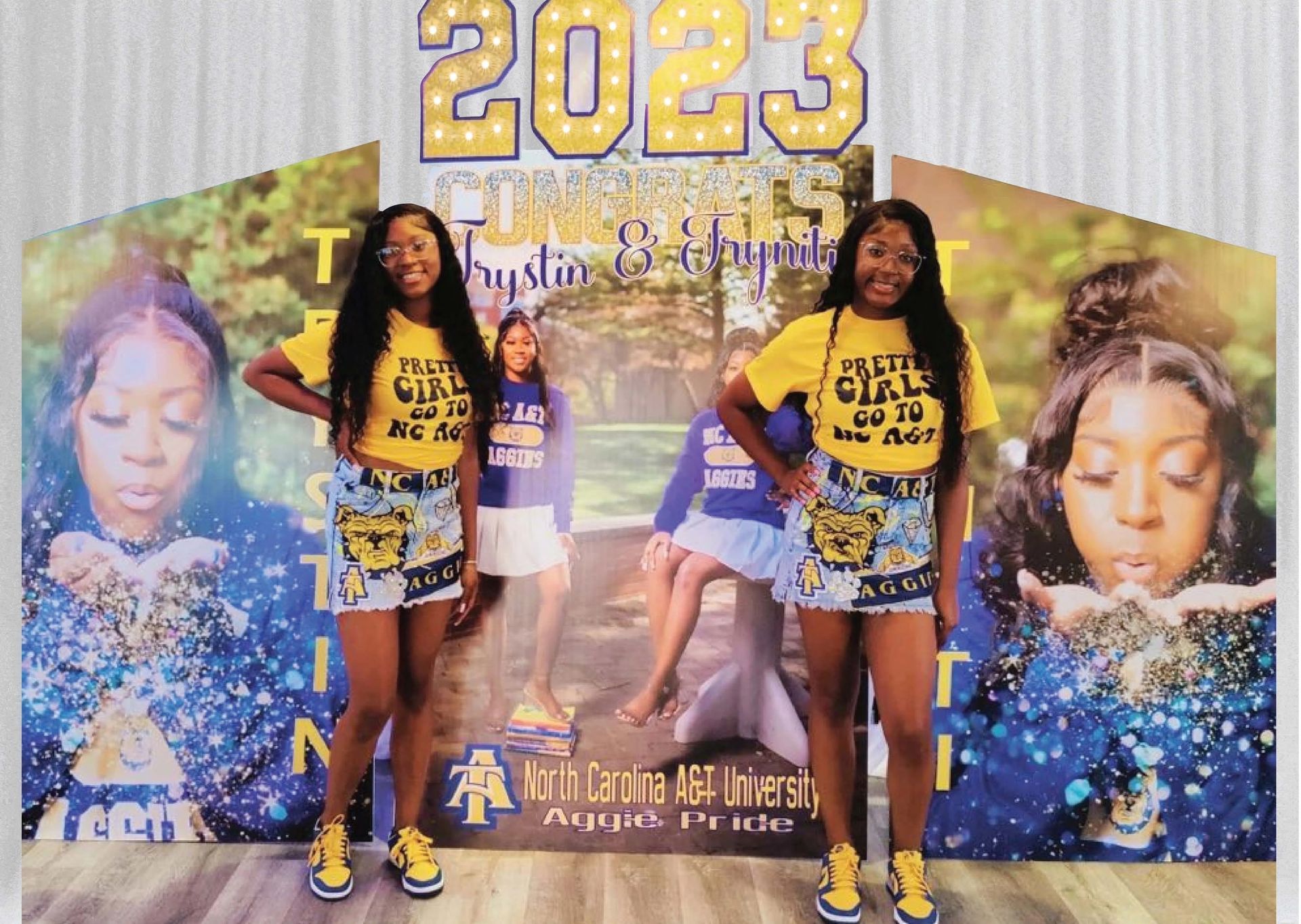Two people in yellow tops and denim skirts pose in front of a backdrop with 