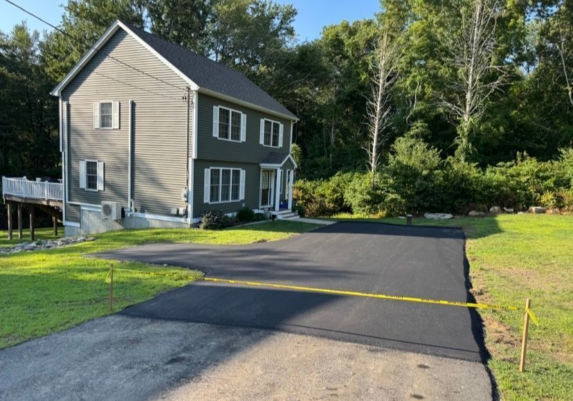Two-story house with a newly paved asphalt driveway. Yellow tape blocks the driveway.