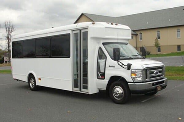 A white bus is parked in a parking lot in front of a building.