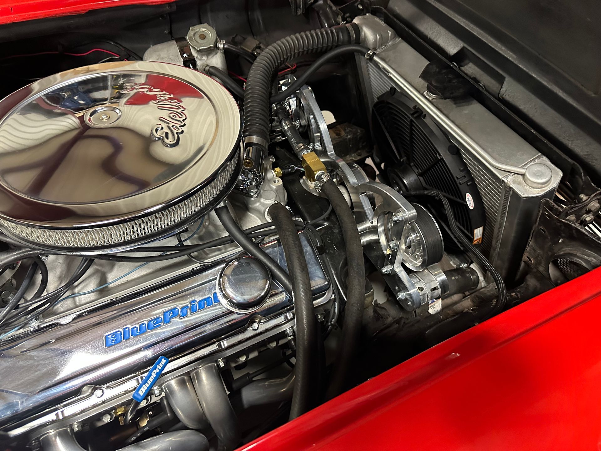 A close up of a red car engine with a chrome air filter.