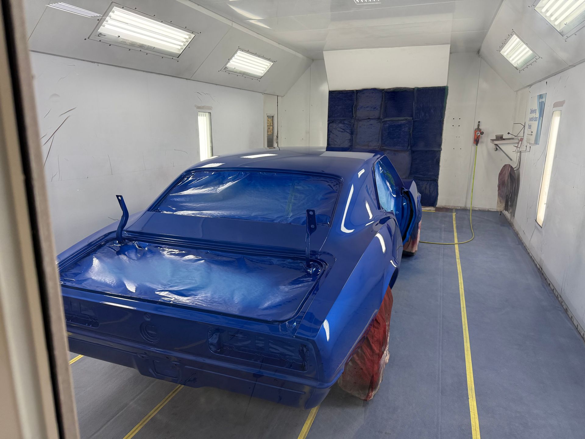 A blue car is painted in a paint booth