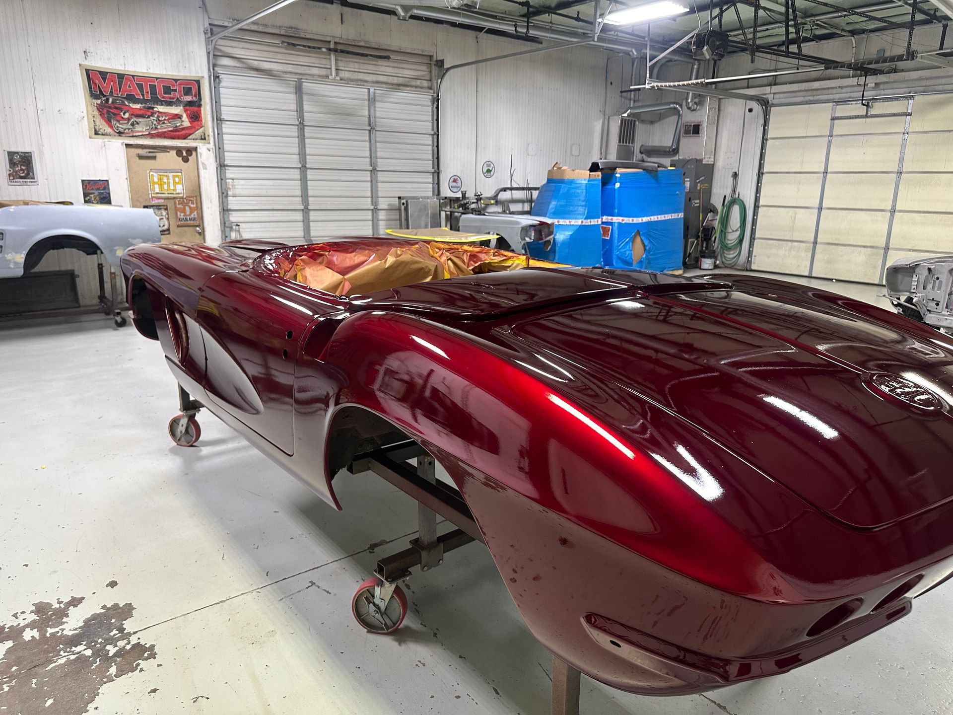 A red sports car is sitting on wheels in a garage.