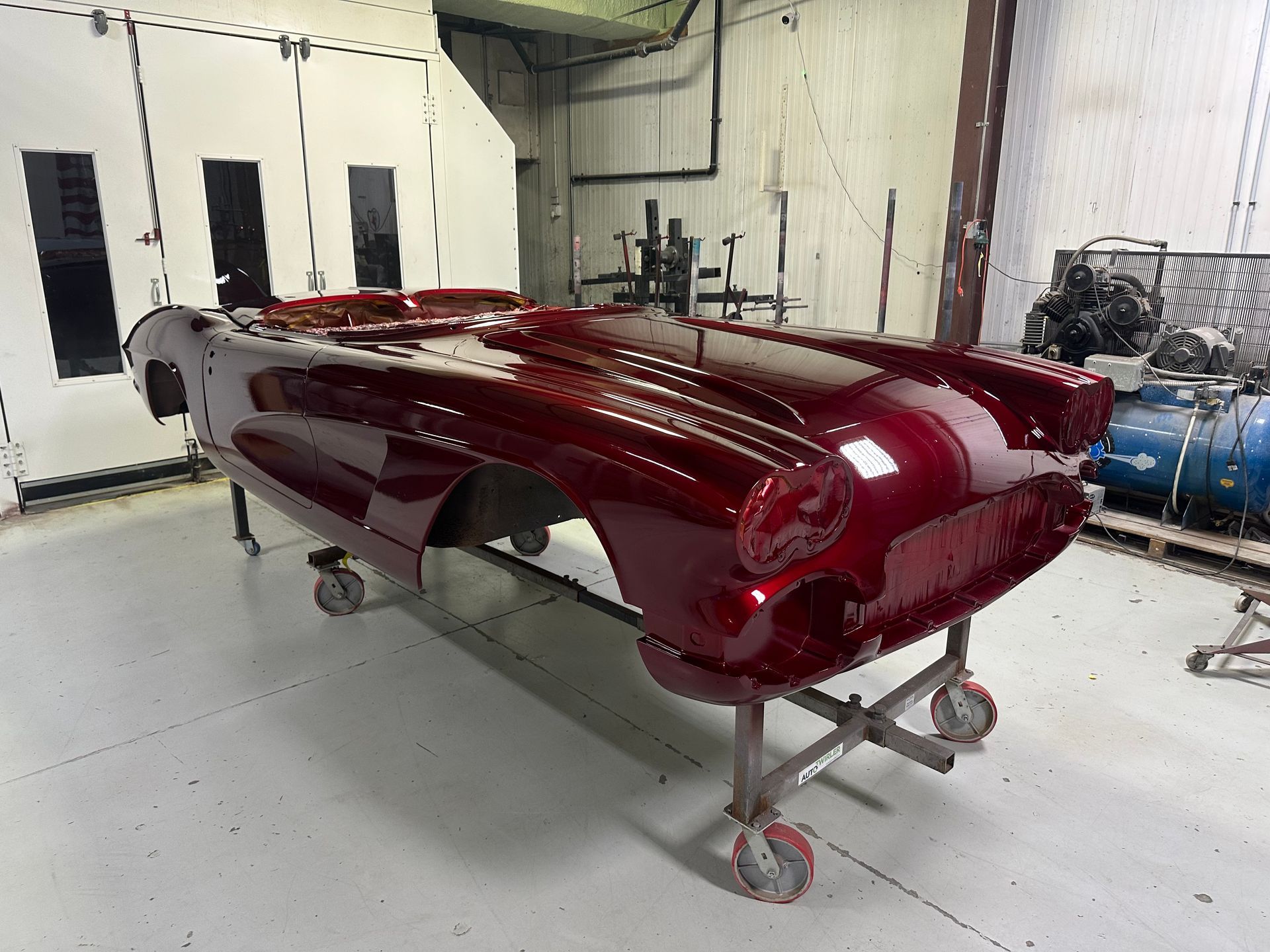 A red car is sitting on a stand in a garage.