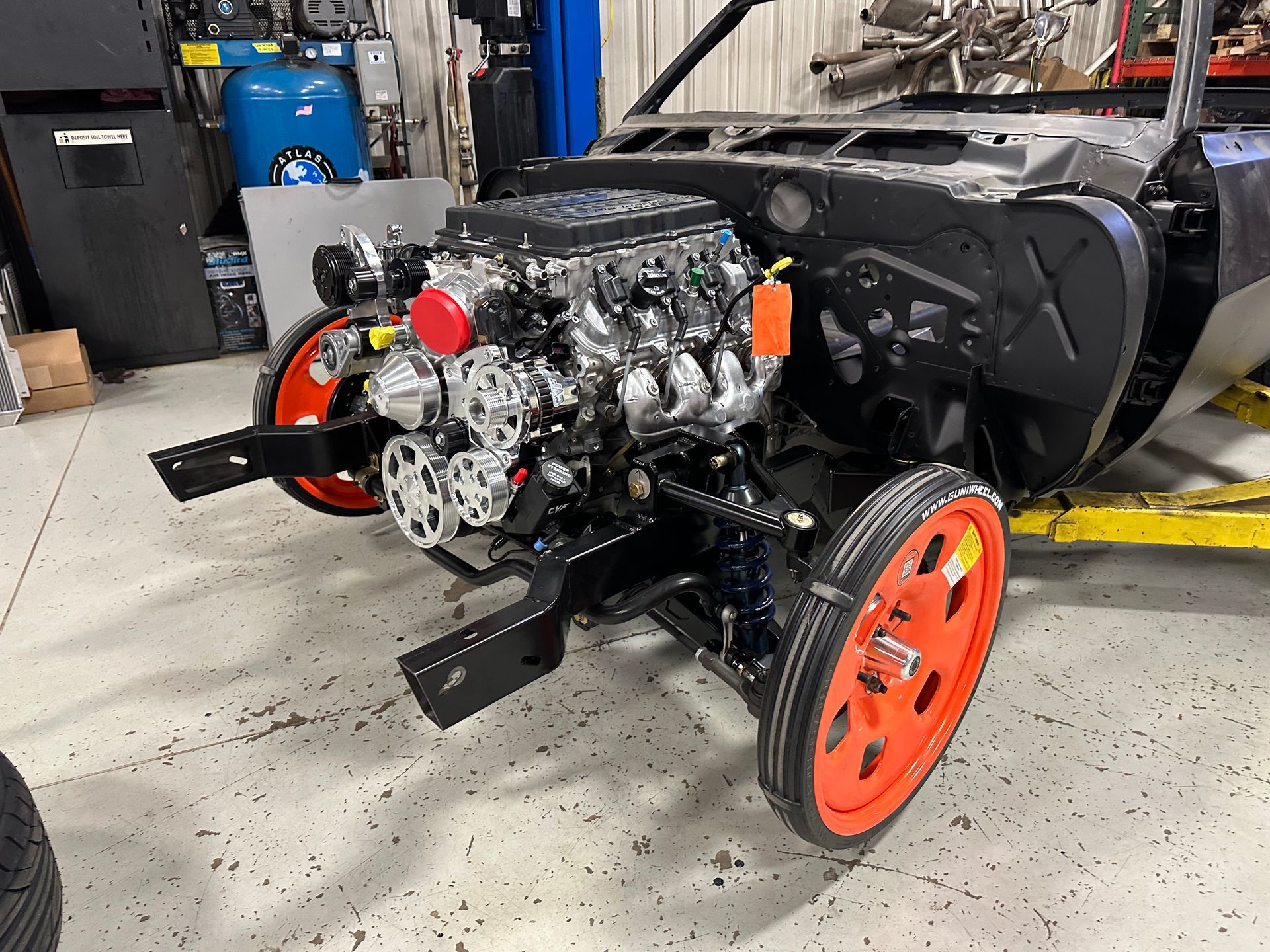 A car engine is sitting on a lift in a garage.