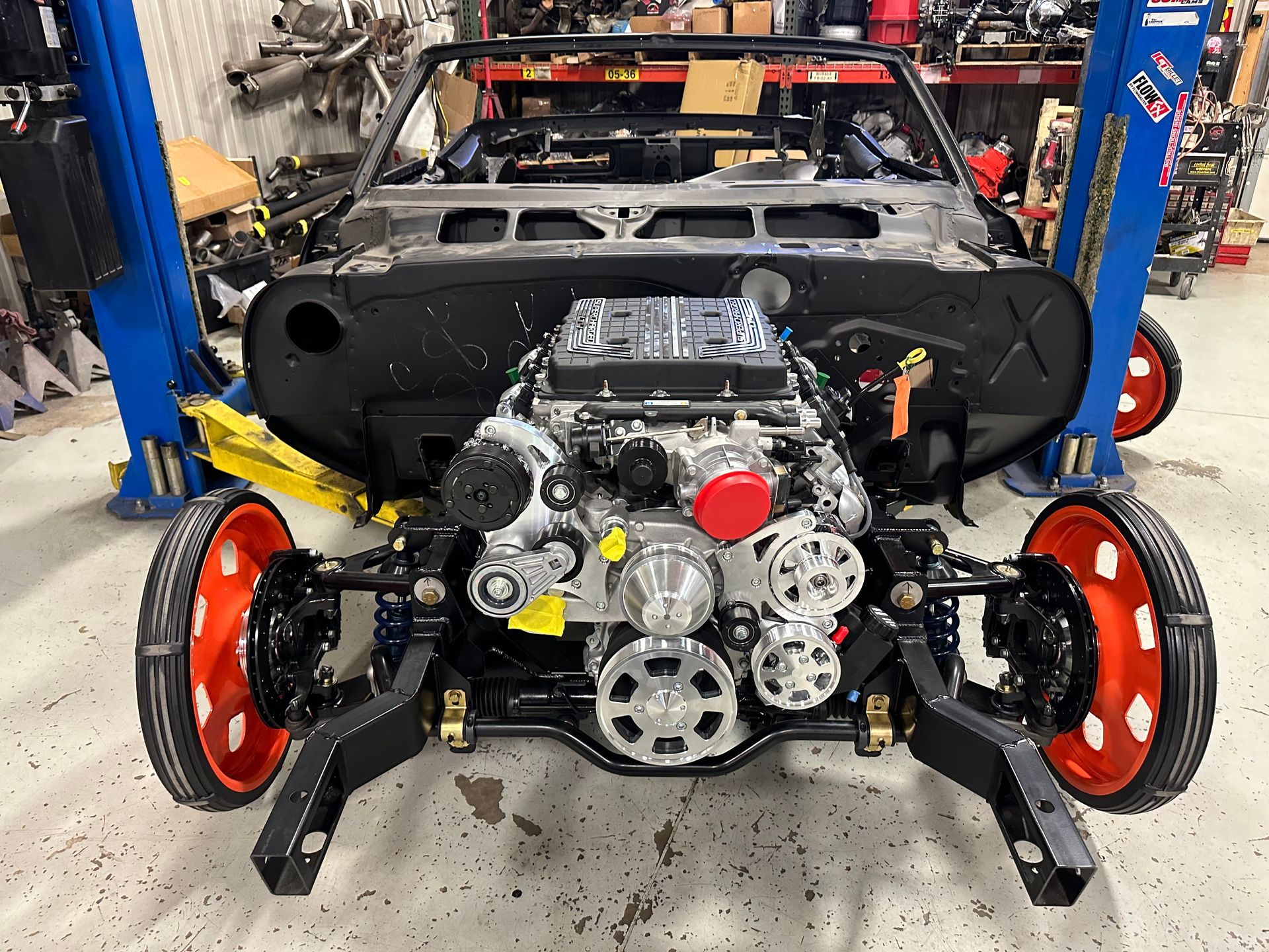 A car engine is sitting on a lift in a garage.