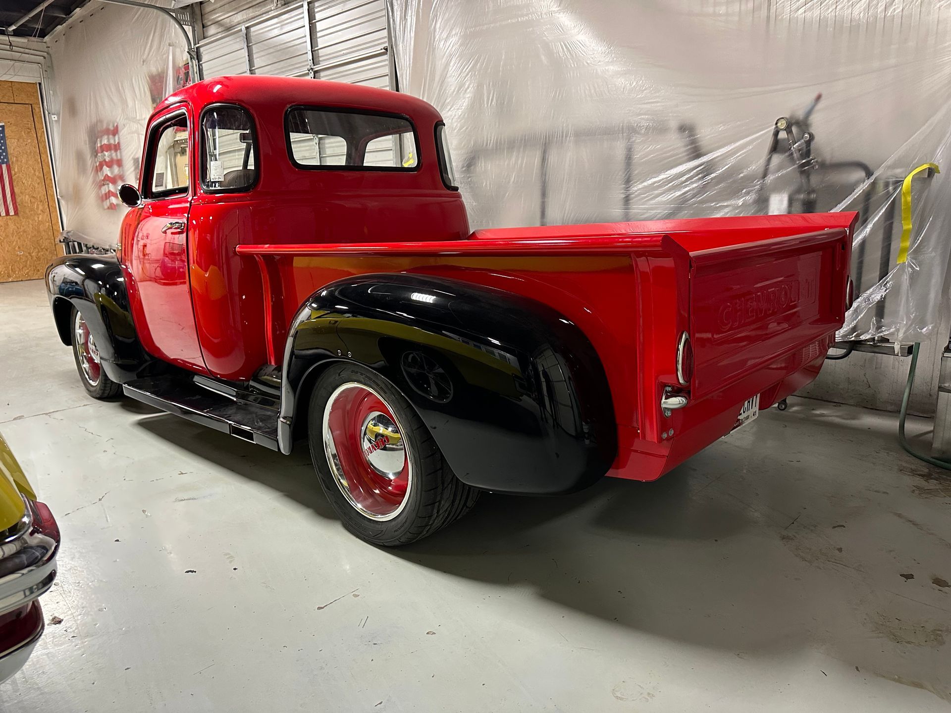A red truck is parked in a garage next to a ladder.