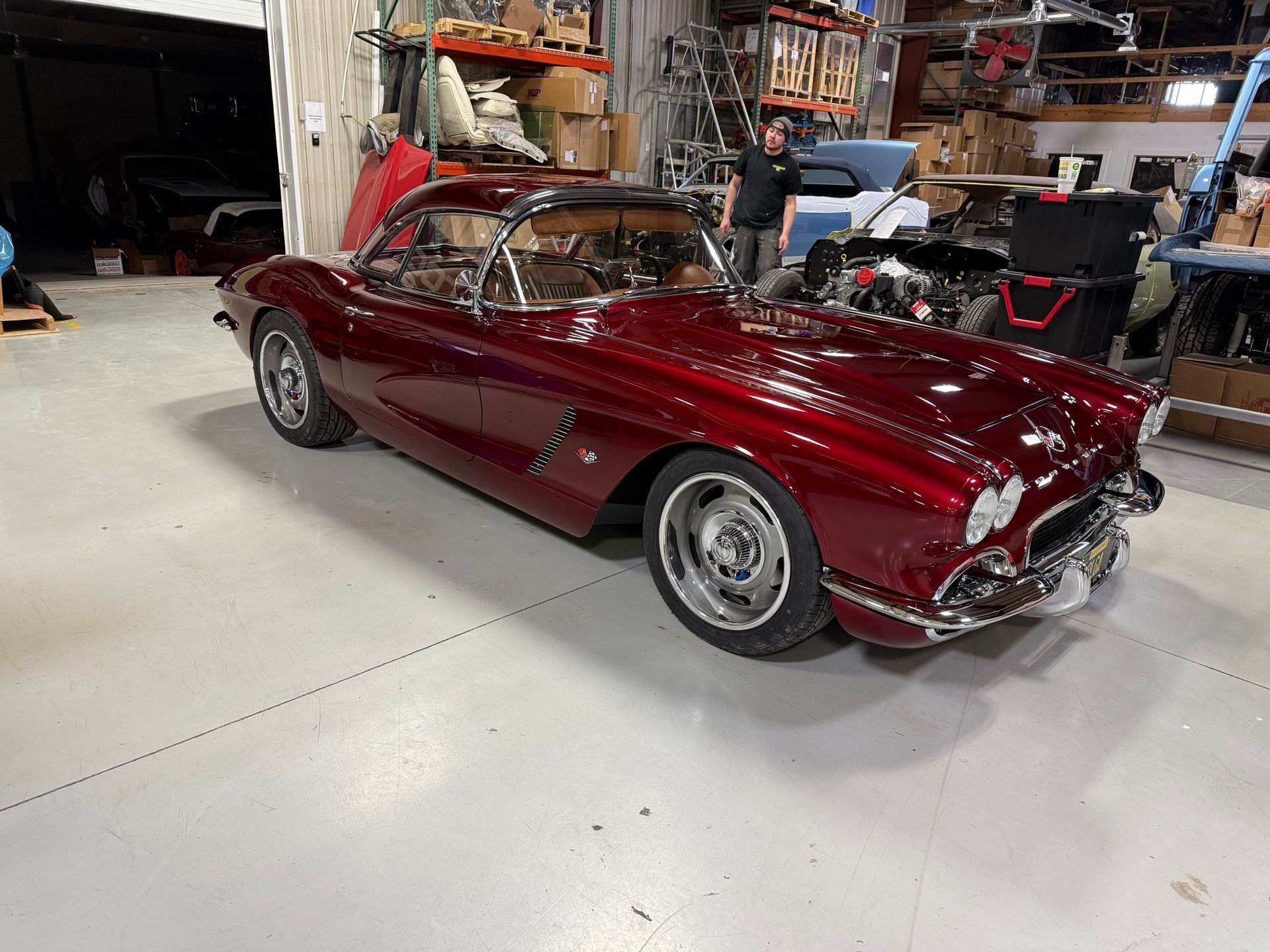 A red corvette is parked in a garage.