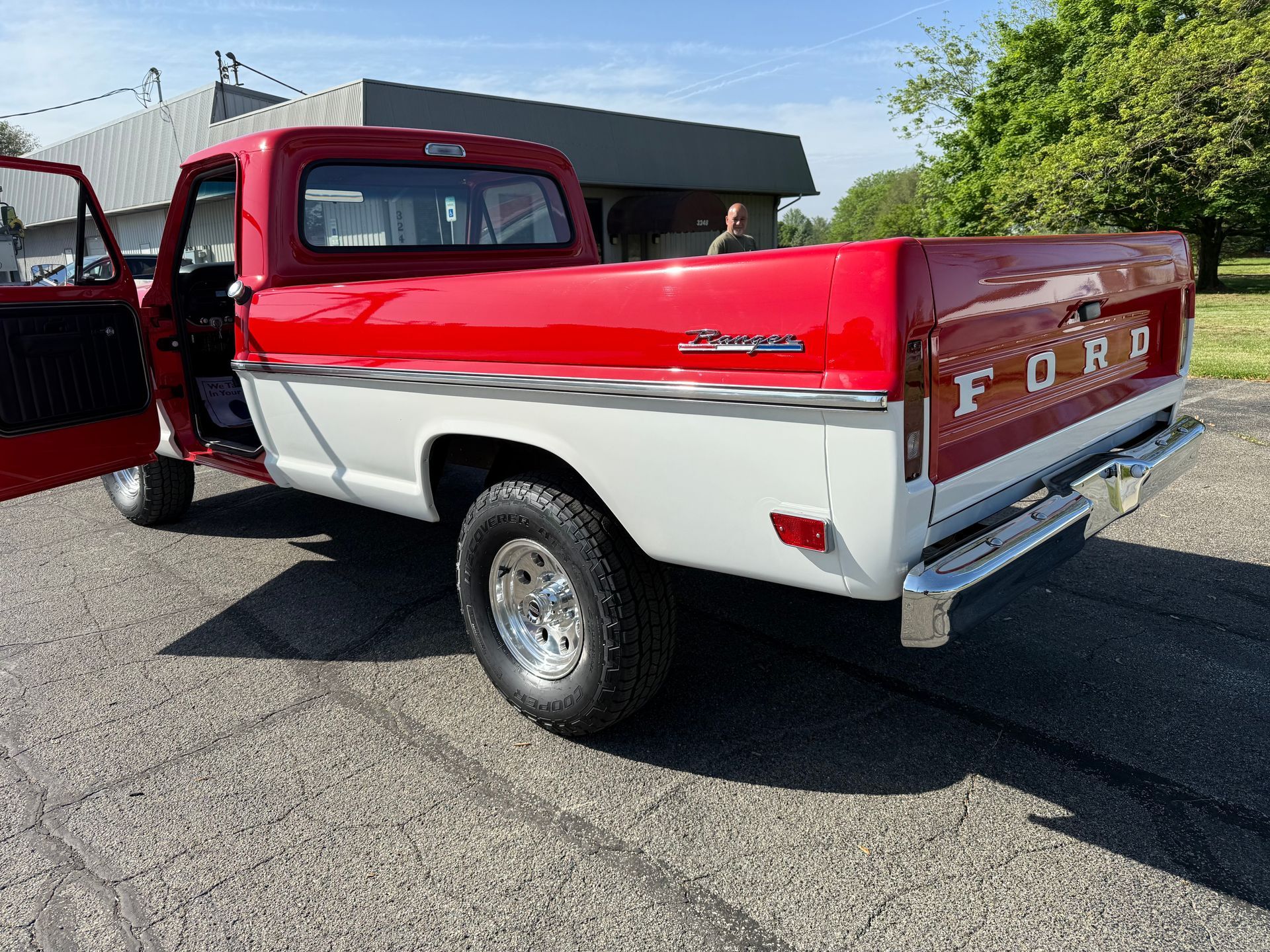 A red and white ford truck is parked on the side of the road.