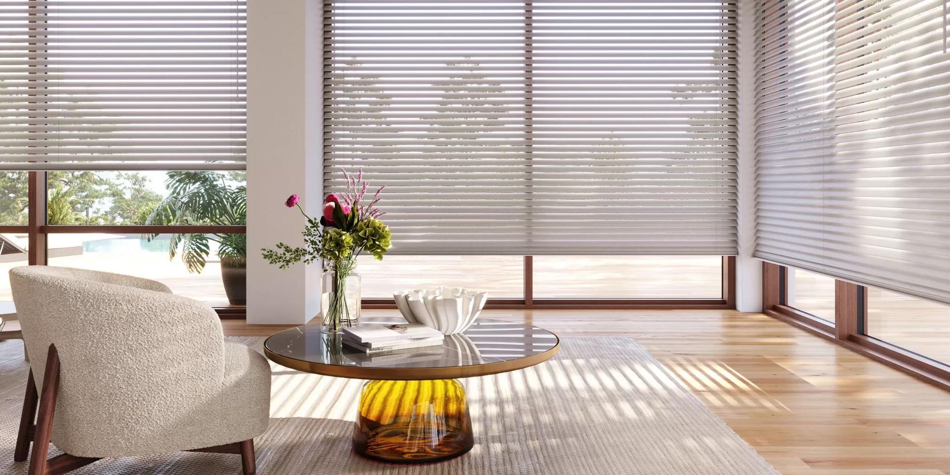Sunlit living room with a white chair, round glass table, flowers, and blinds casting striped shadows