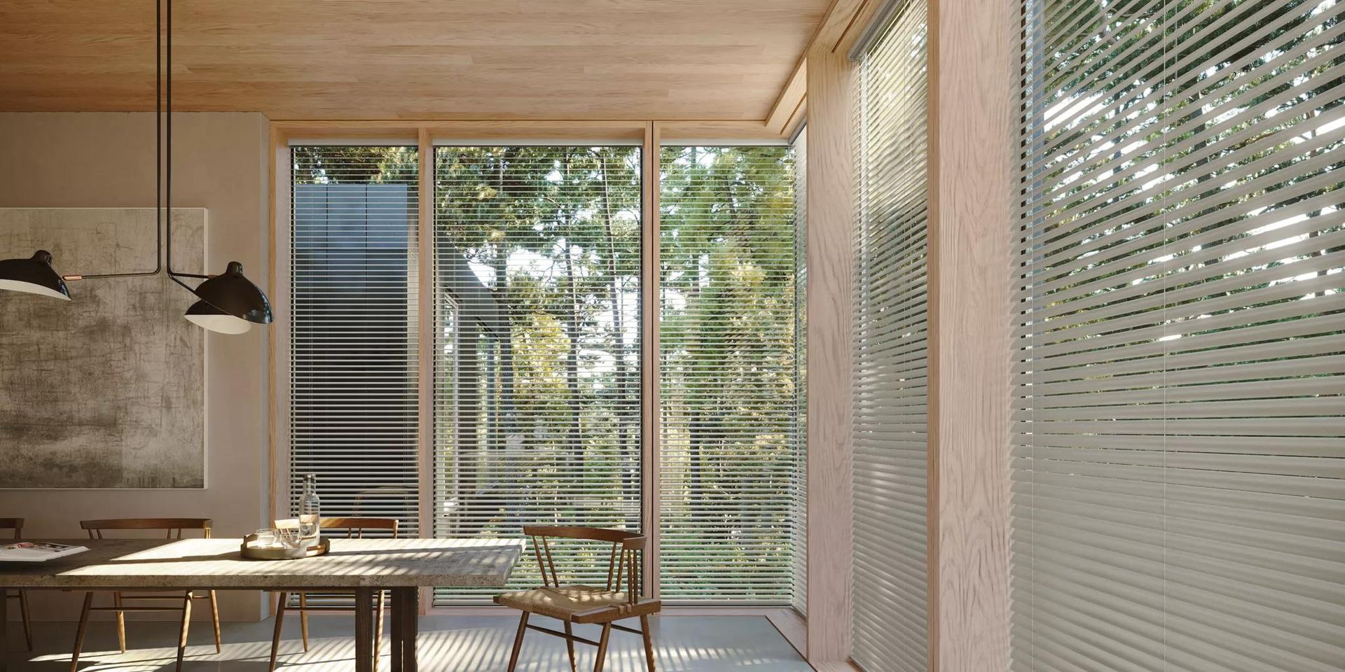 Modern dining area with wooden table, pendant lights, and floor-to-ceiling windows opening to a green garden