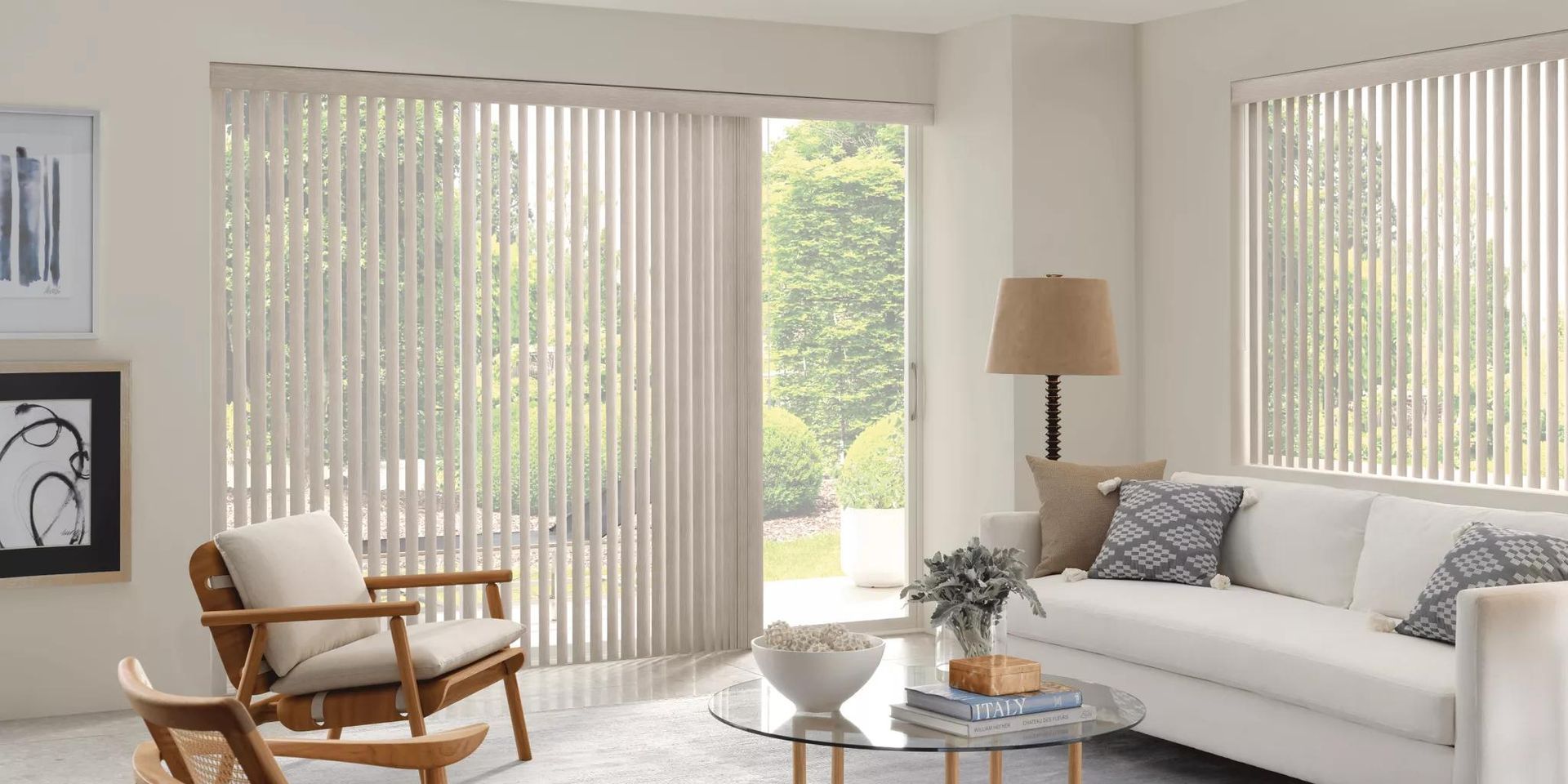 Bright living room with white sofa, wood chair, vertical blinds, lamp, and coffee table.