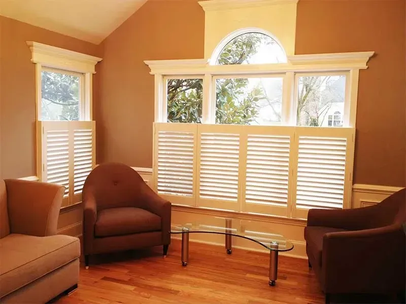 Living room with beige walls, large windows, sofas, chairs, and a glass coffee table