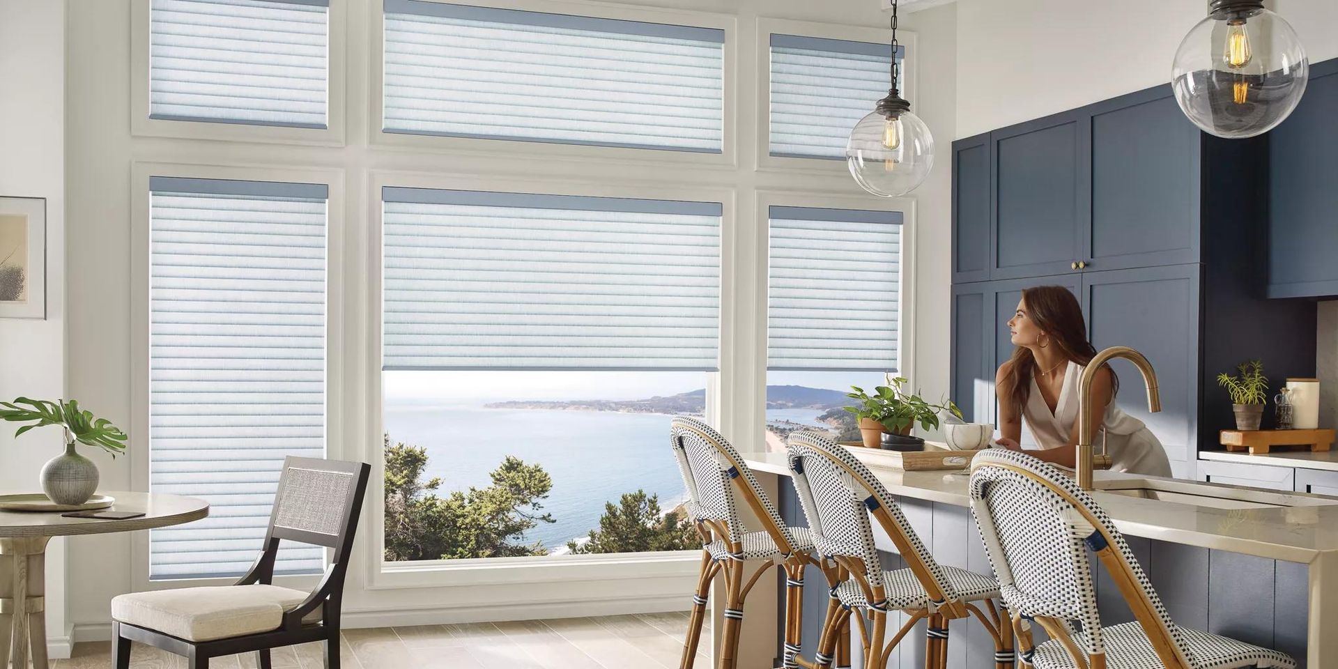 Bright modern kitchen with a woman at the island, large windows, and ocean view