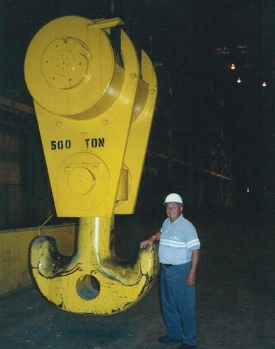 A man standing next to a hook that says 500 ton