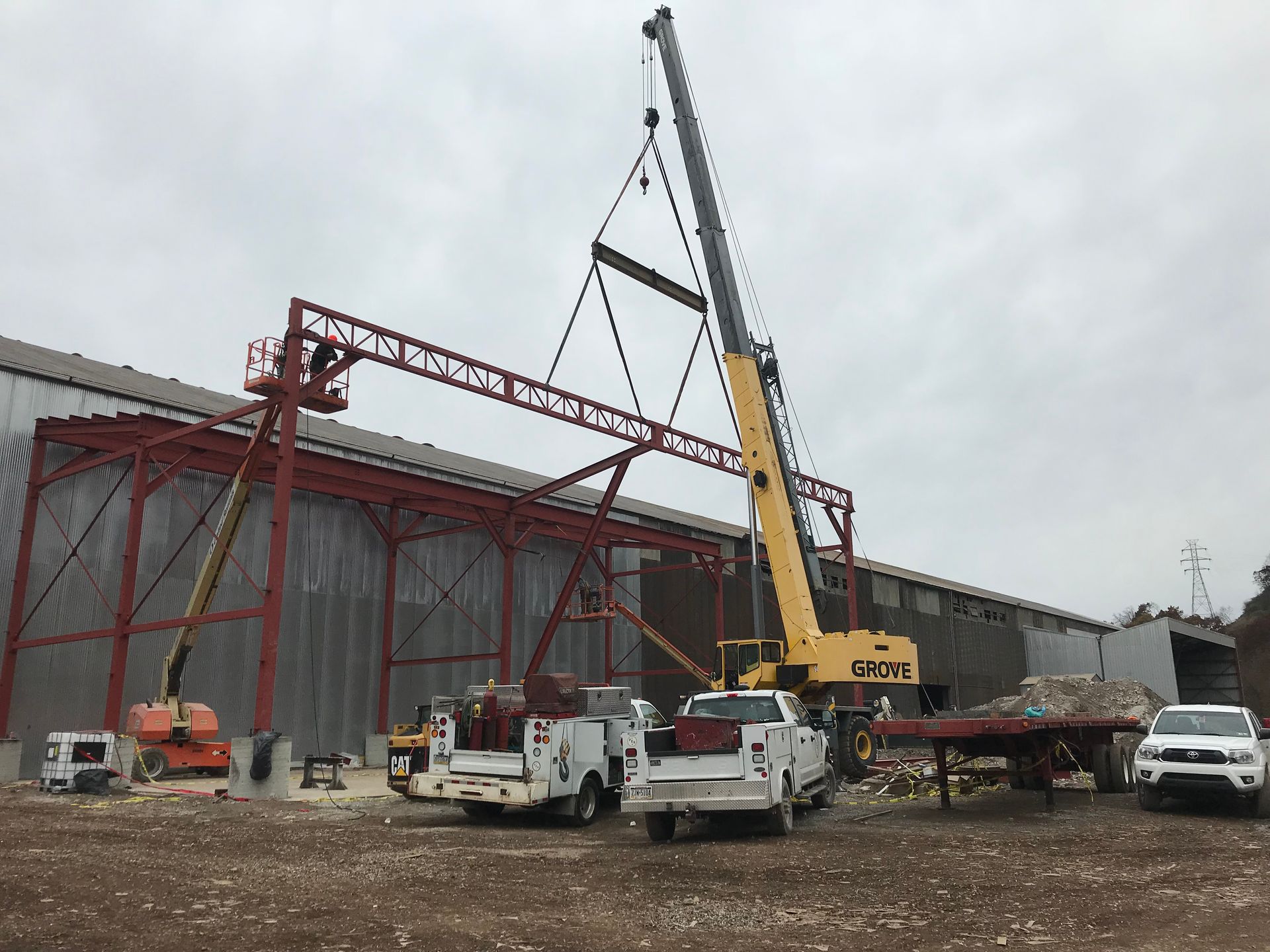 A large crane is lifting a metal structure in front of a building.